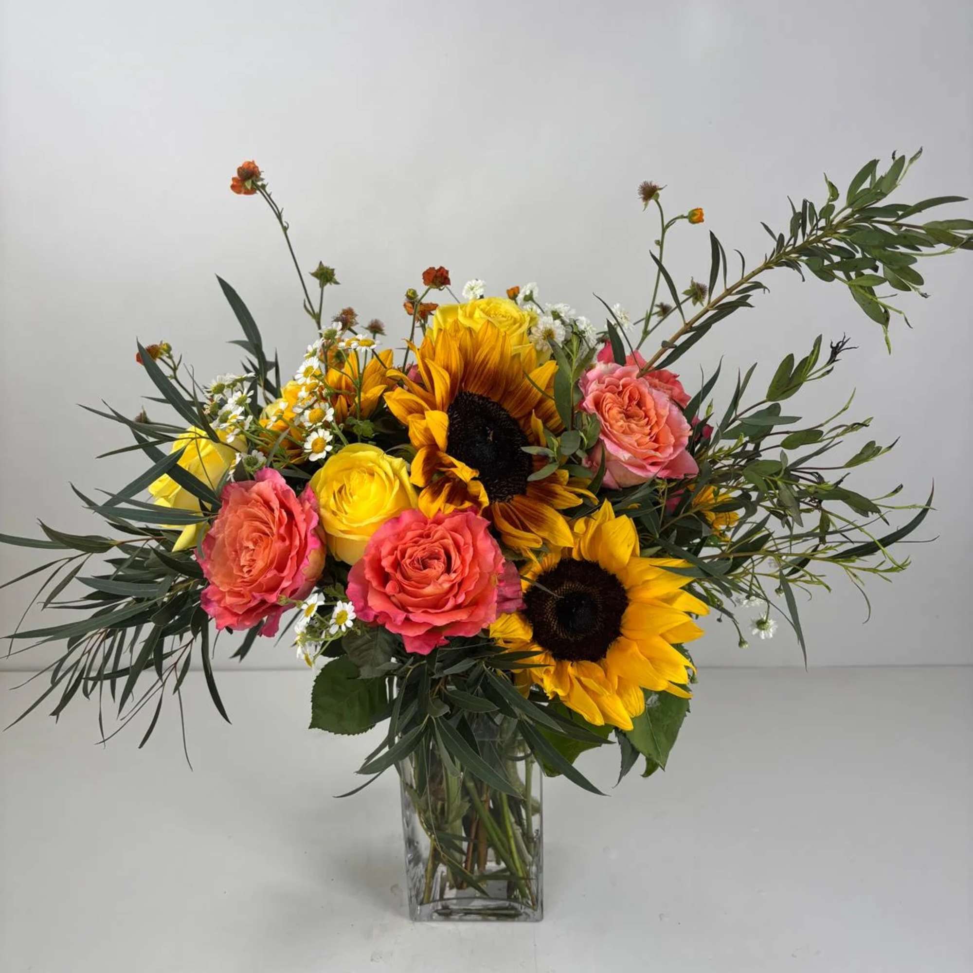 Bouquet of sunflowers and pink roses in a clear glass vase