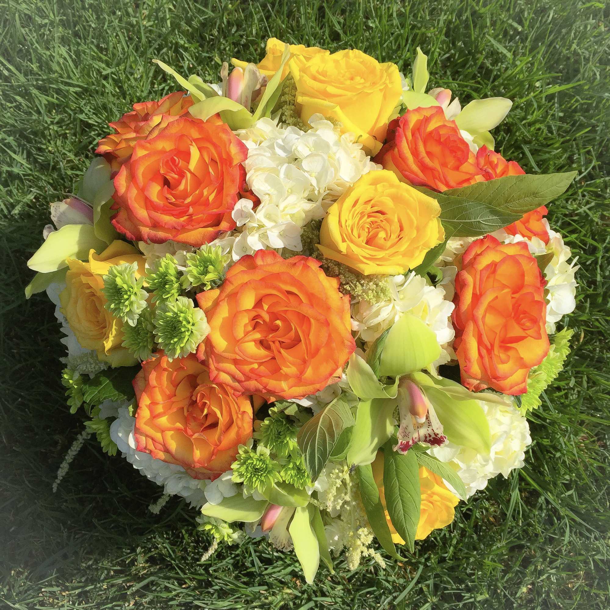 Bouquet of orange and yellow roses with white hydrangea and green accents