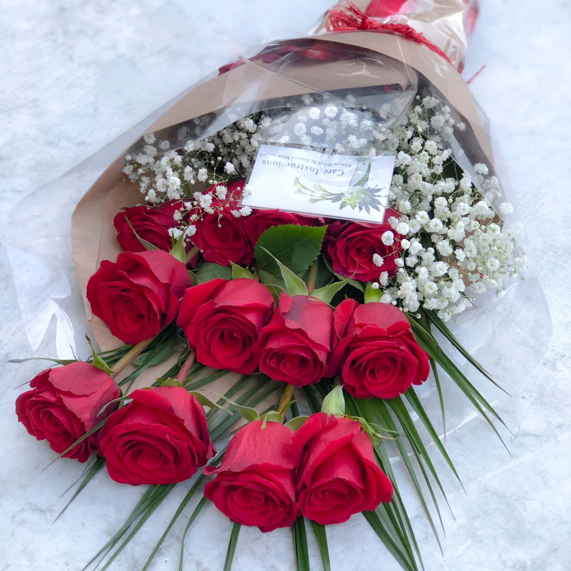 Bouquet of red roses with white baby's breath in brown paper