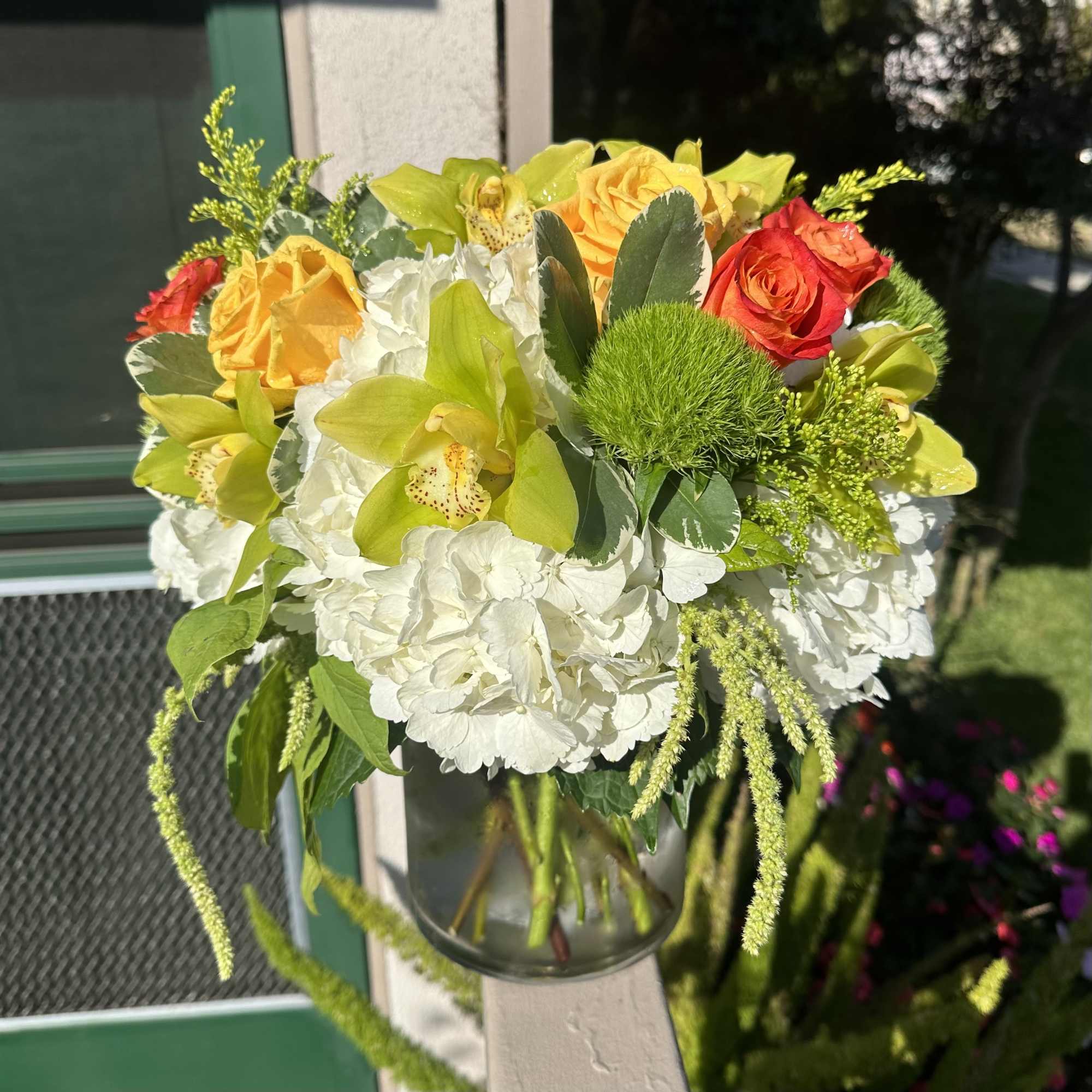 Bouquet of yellow and red roses with white hydrangeas in a glass vase