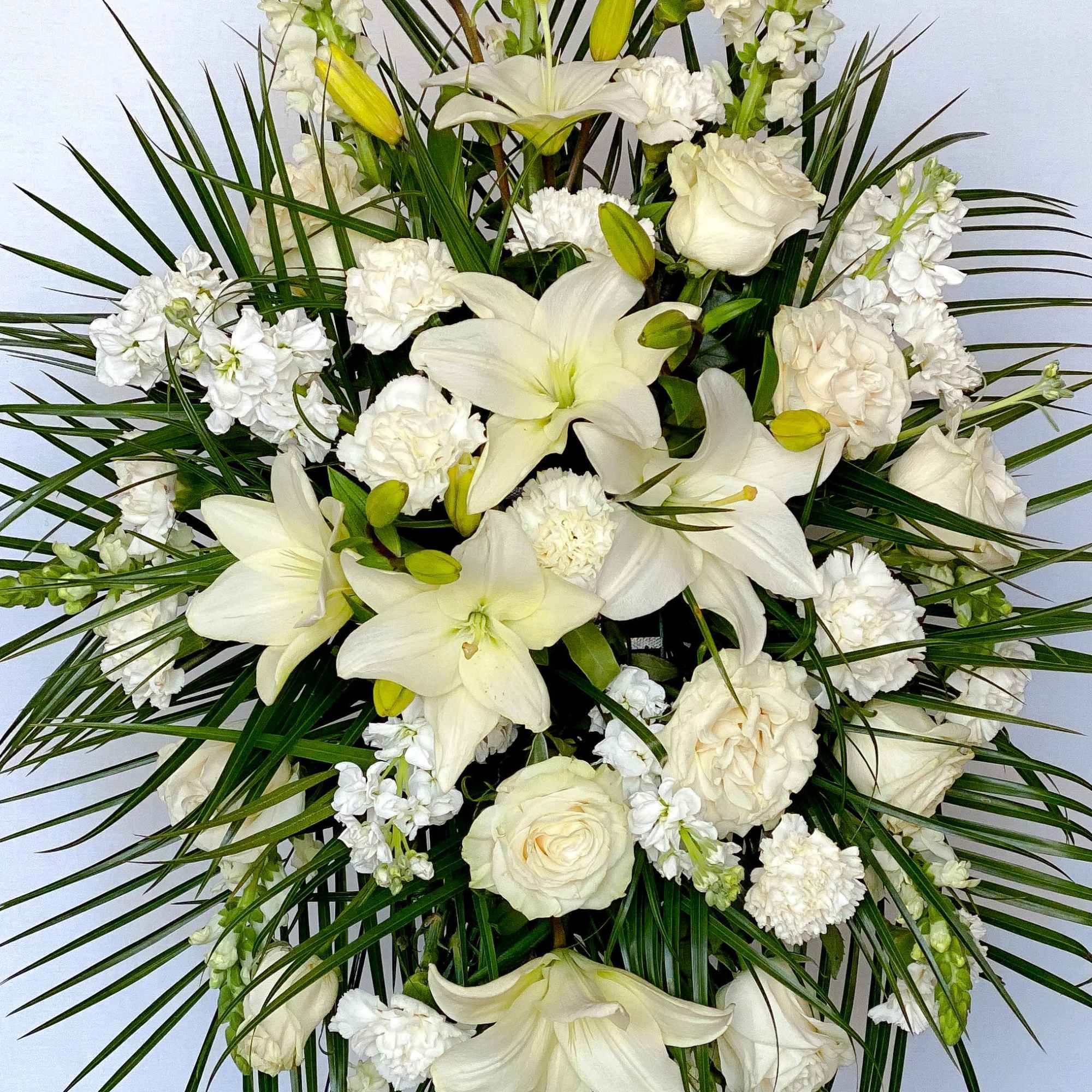 White lilies and roses arranged with greenery in a tall spray