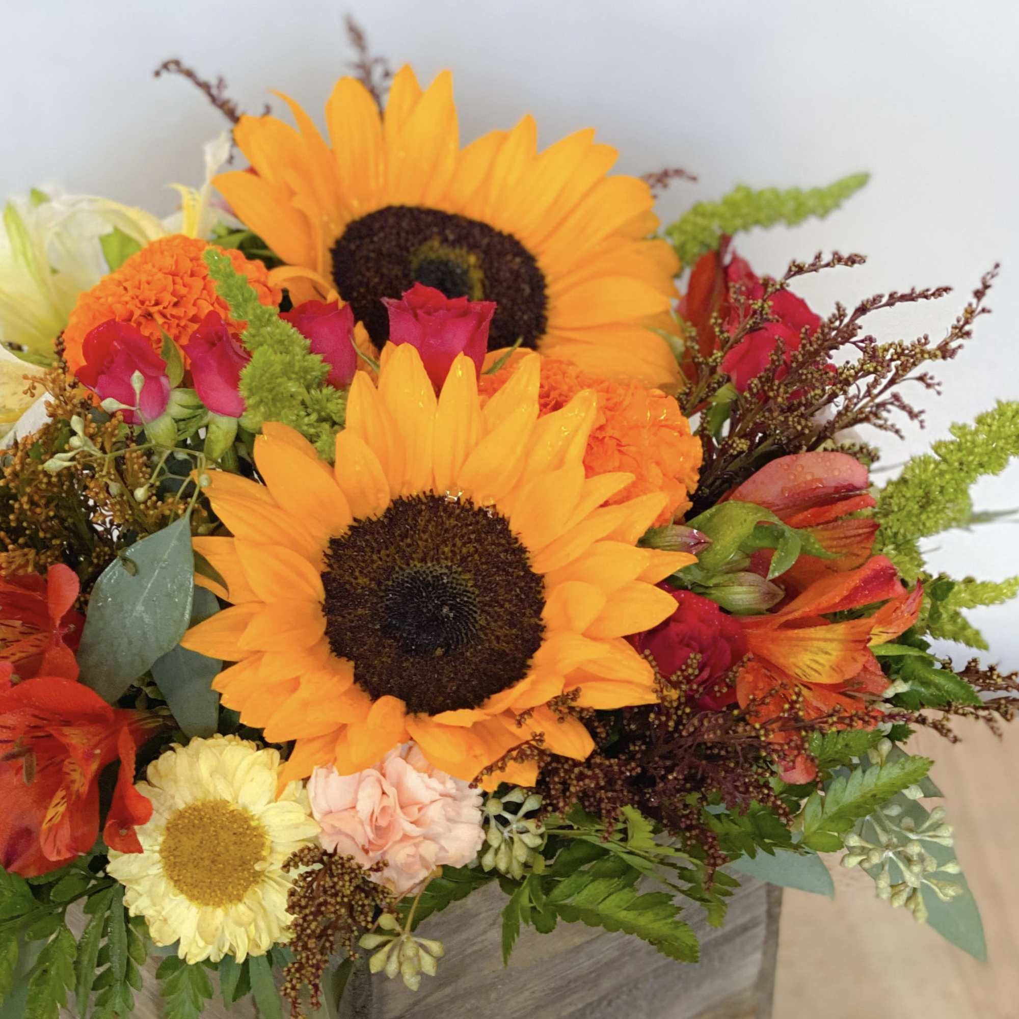 Bouquet with sunflowers, roses, and mixed blooms in a container