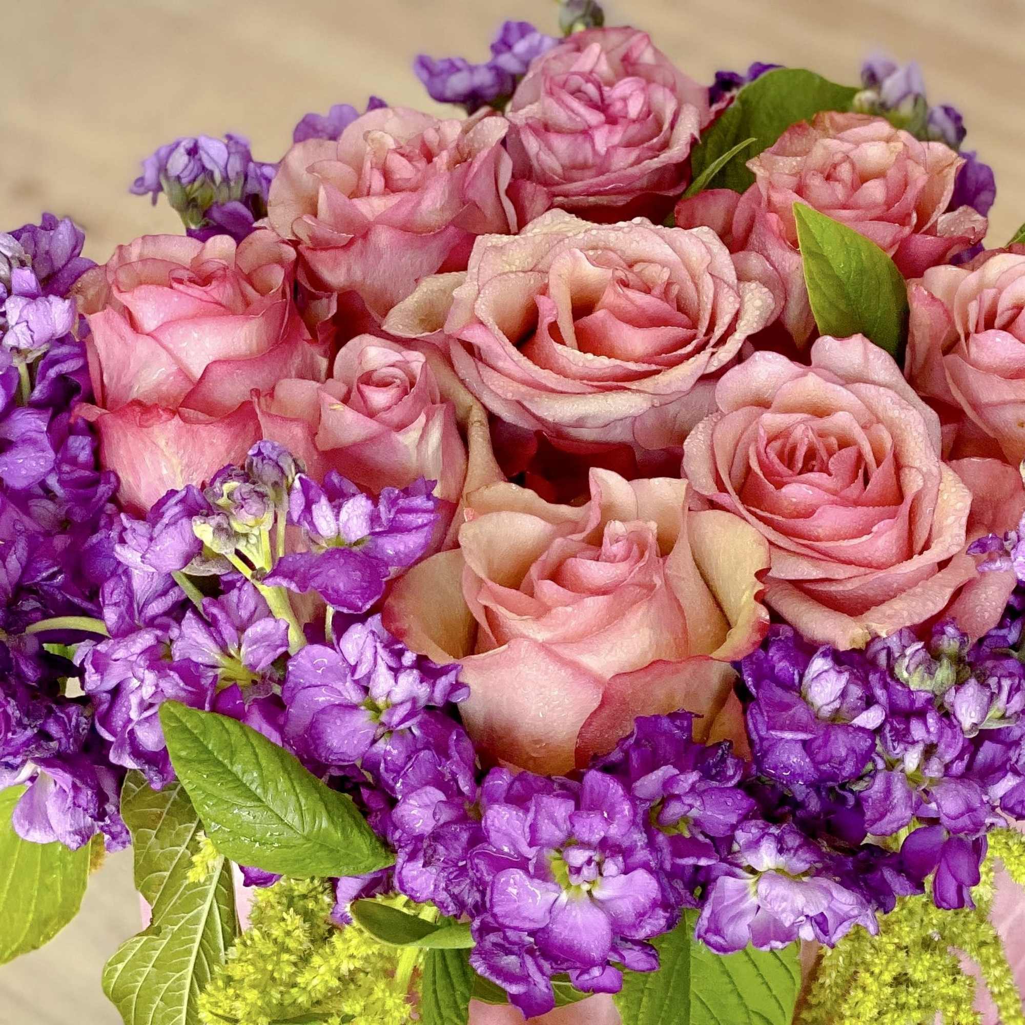 Pink roses surrounded by purple flowers in a bouquet