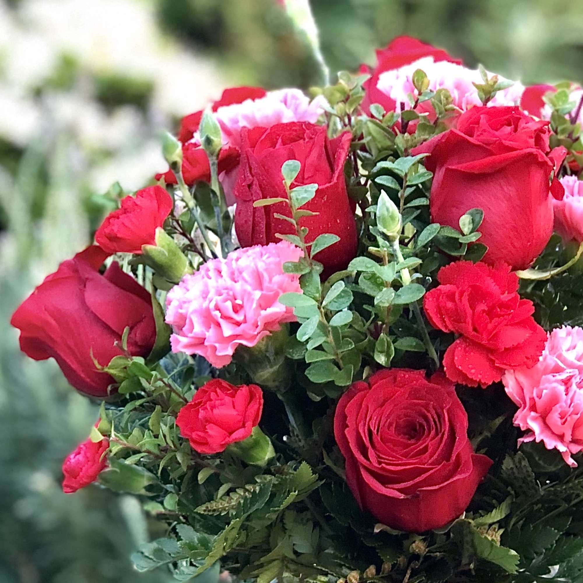 Bouquet of red roses and pink carnations with greenery