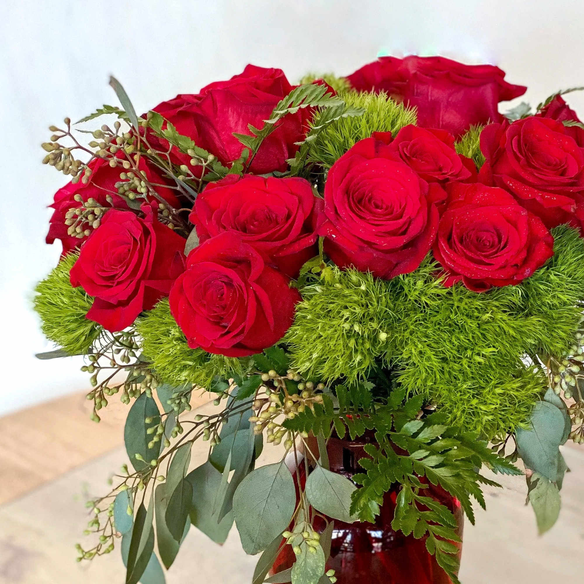 Bouquet of red roses with bright green filler in a vase