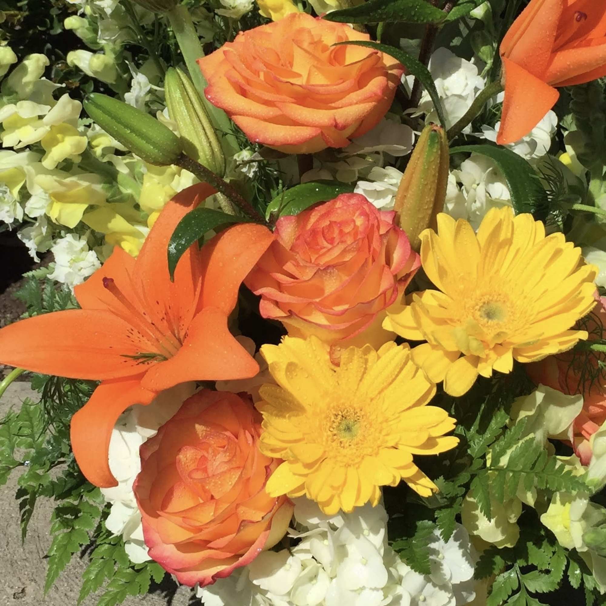 Orange roses and yellow daisies with orange lilies in a mixed bouquet