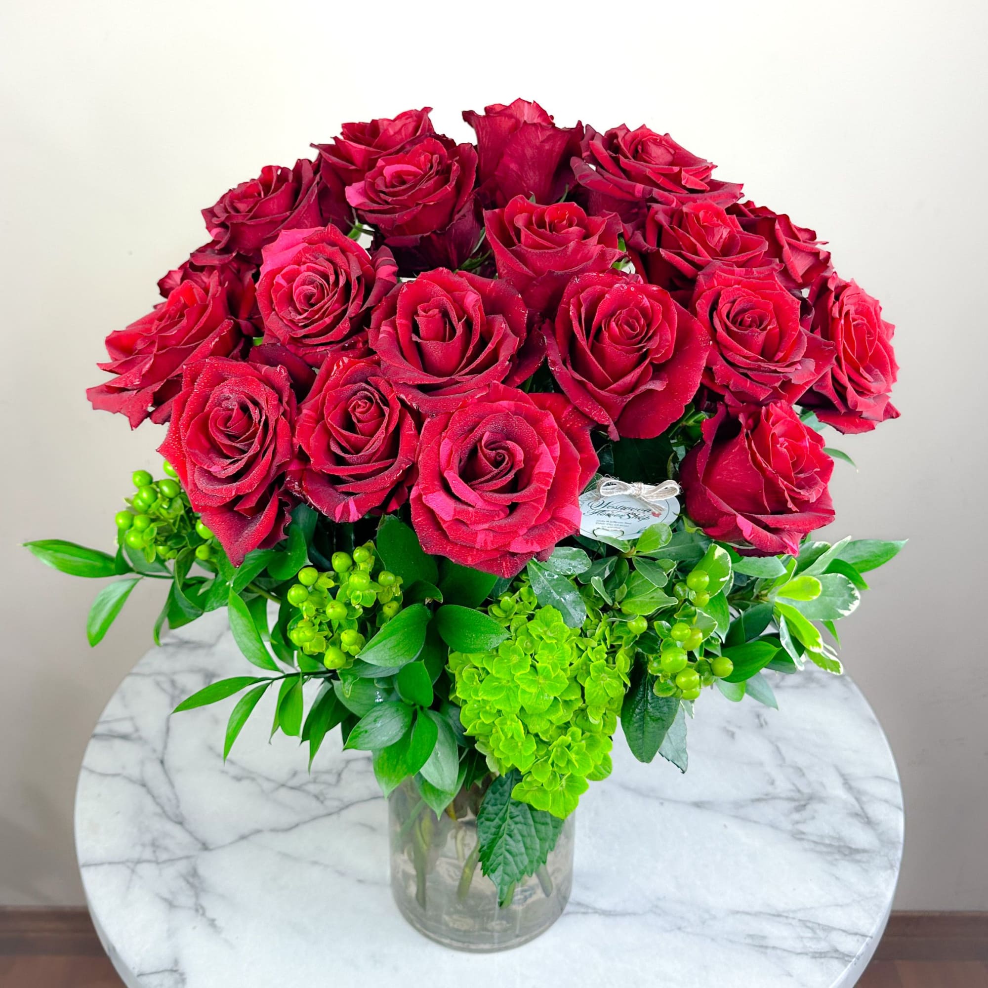 Bouquet of red roses with green filler in a clear glass vase