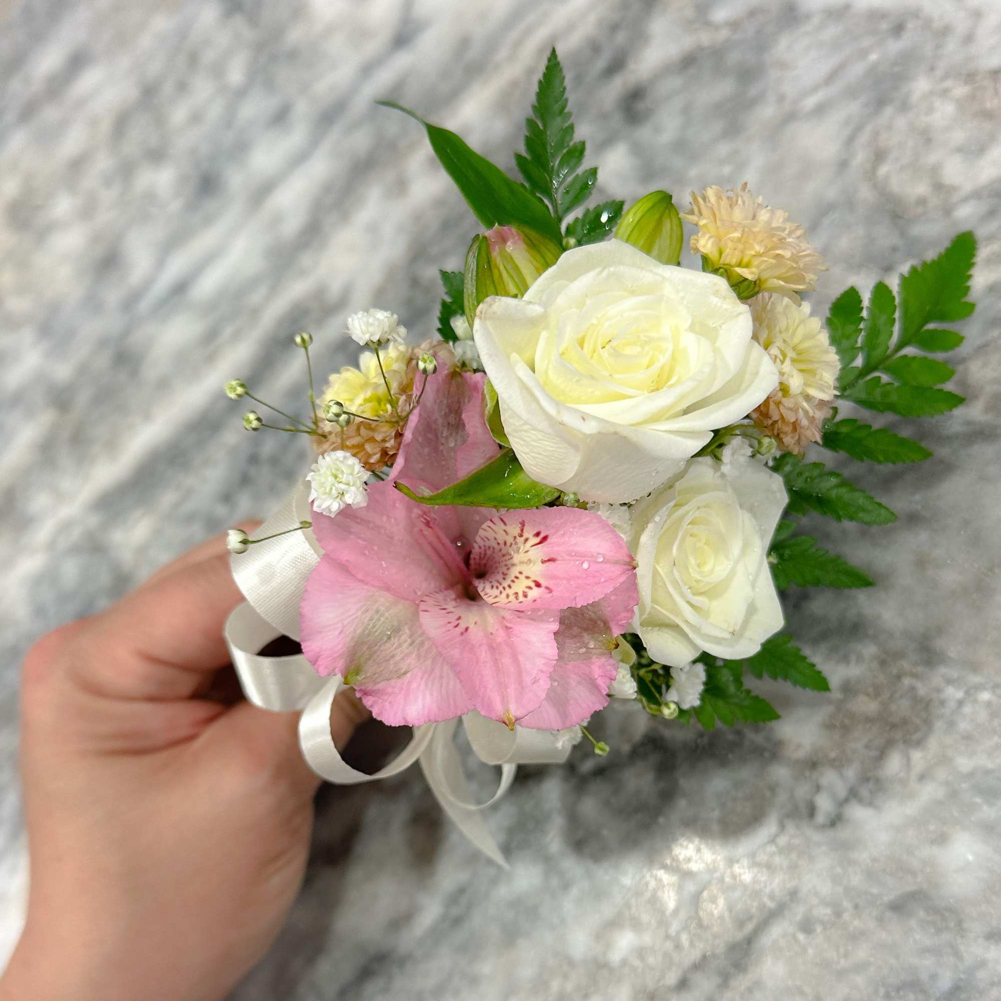 Small pink and white floral corsage with ribbon