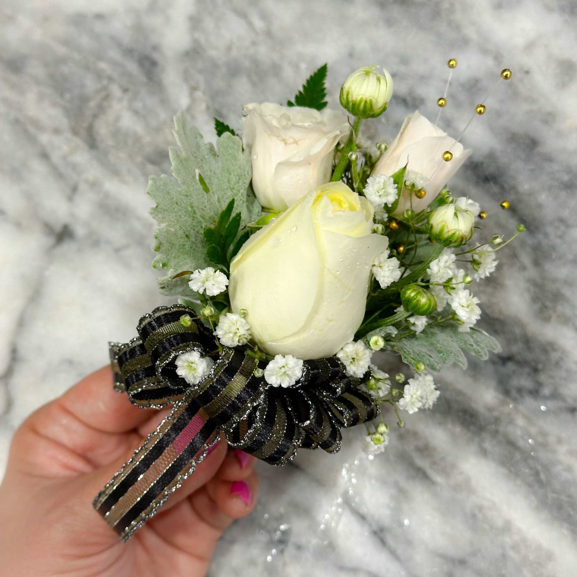 White rose boutonniere with baby's breath and black ribbon