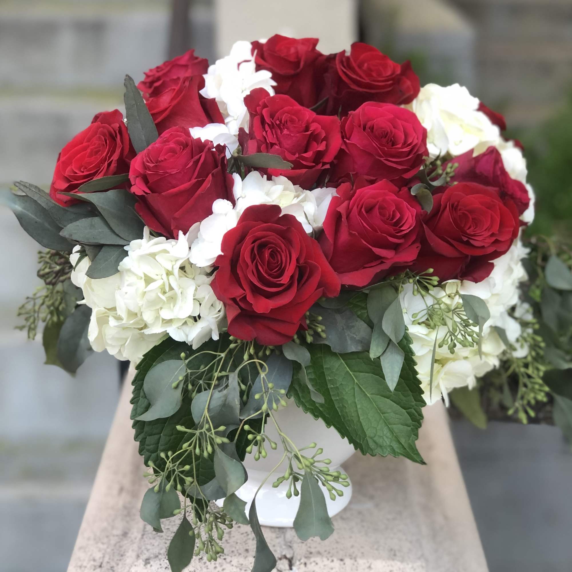 Red roses and white hydrangeas in a white vase