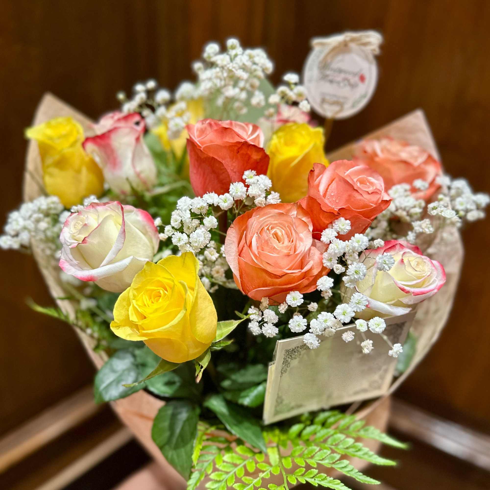 Bouquet of multicolored roses with baby's breath in brown paper