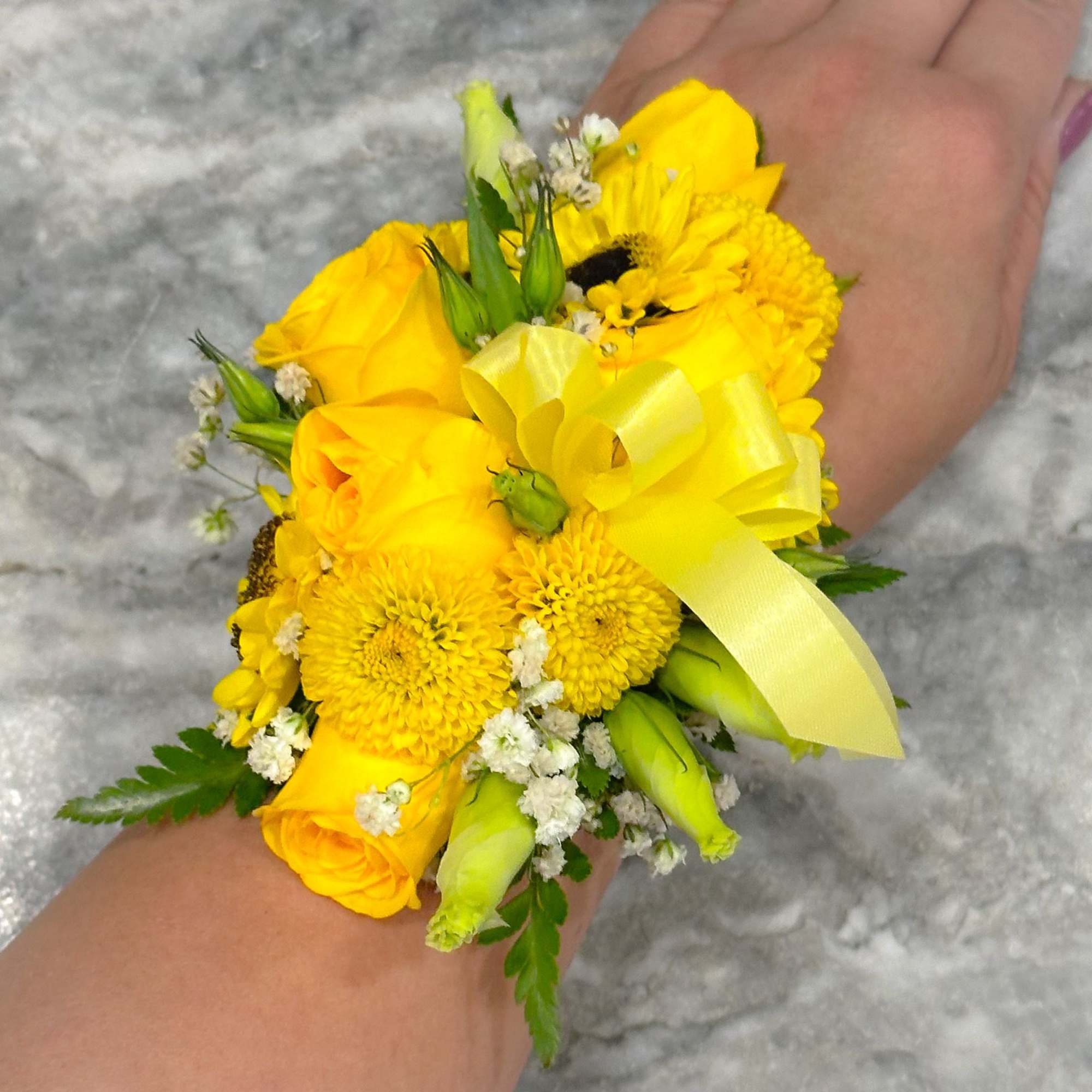 Yellow wrist corsage with roses and mums tied with a ribbon