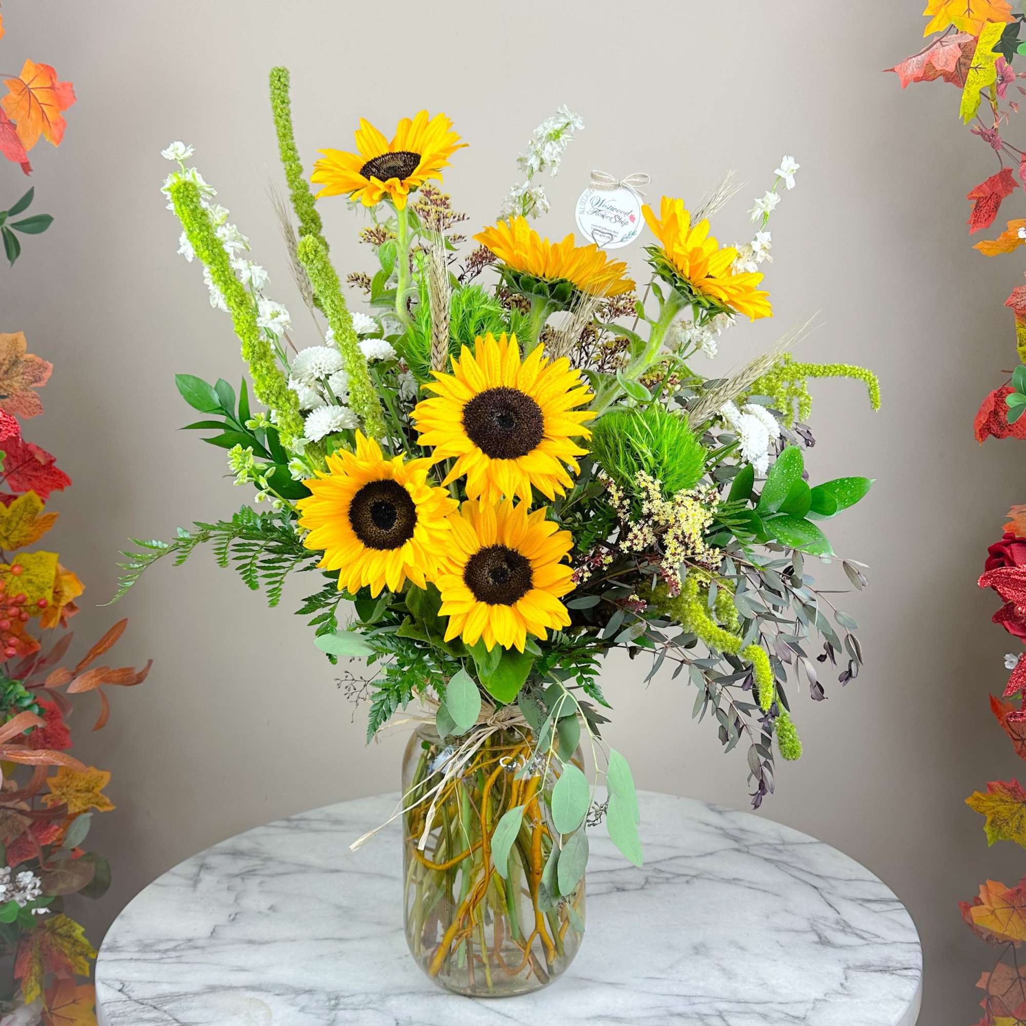 Sunflower bouquet in a clear glass vase with mixed greenery