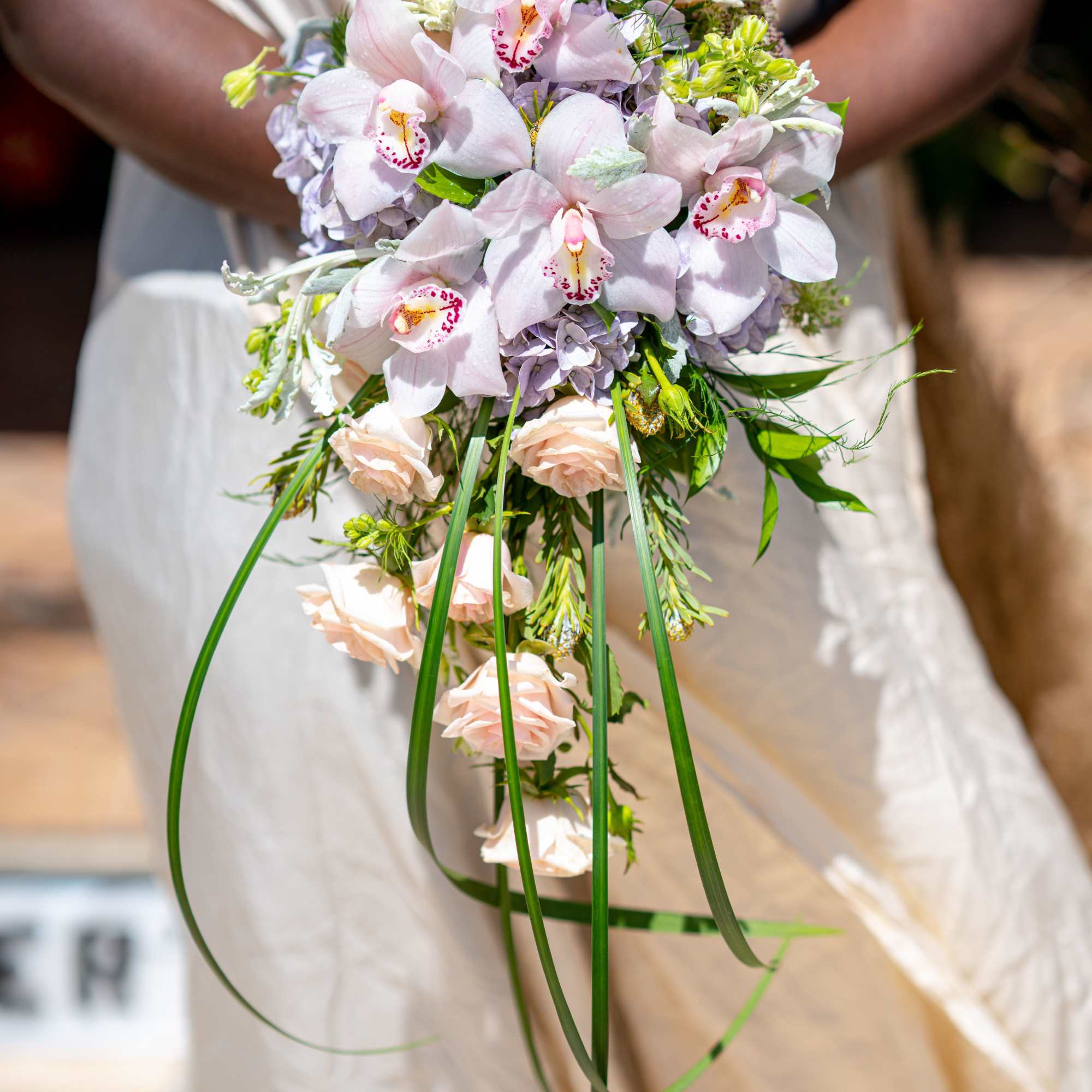 Bridal bouquet of pale pink orchids and roses with long trailing greenery