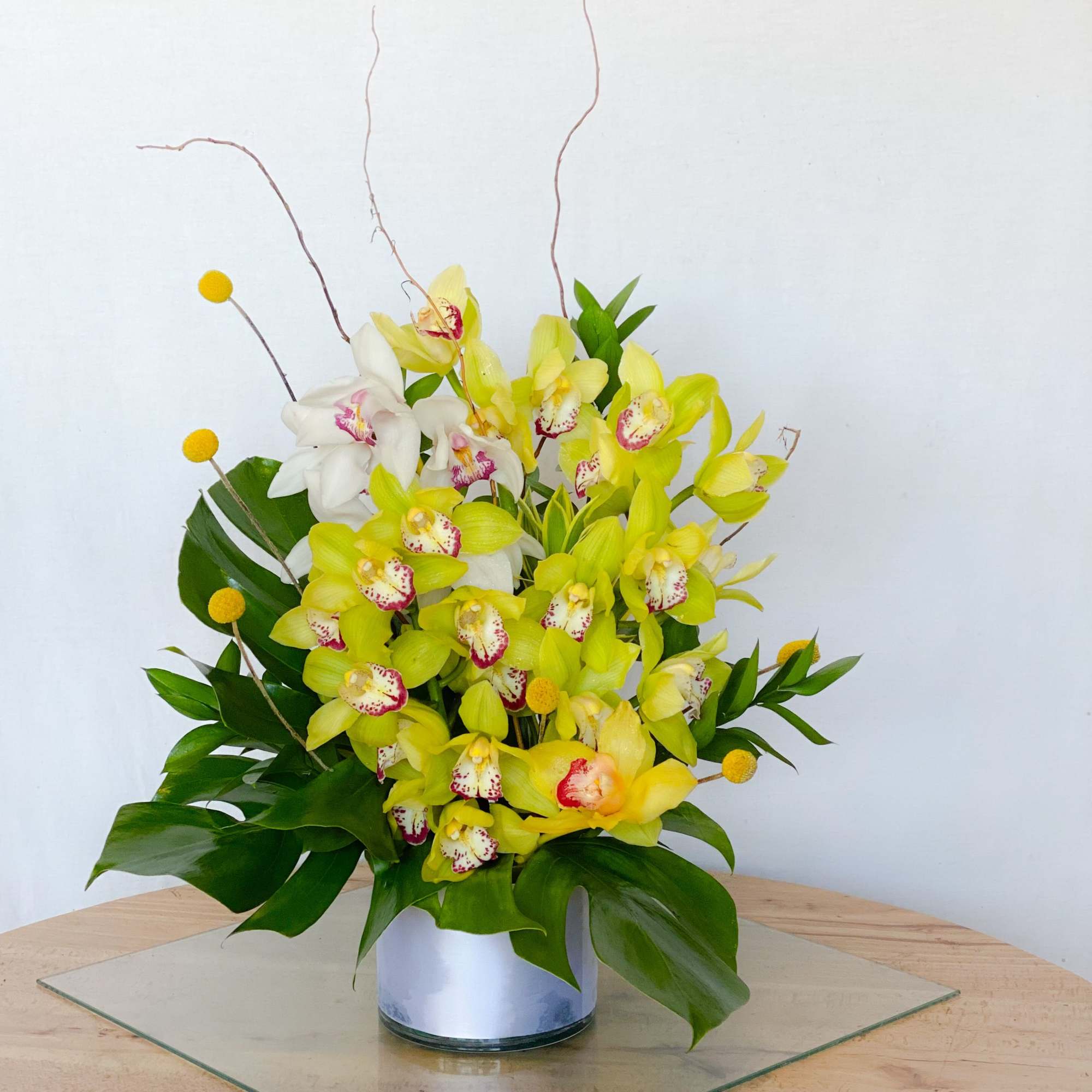 Yellow and white orchid arrangement in a silver vase