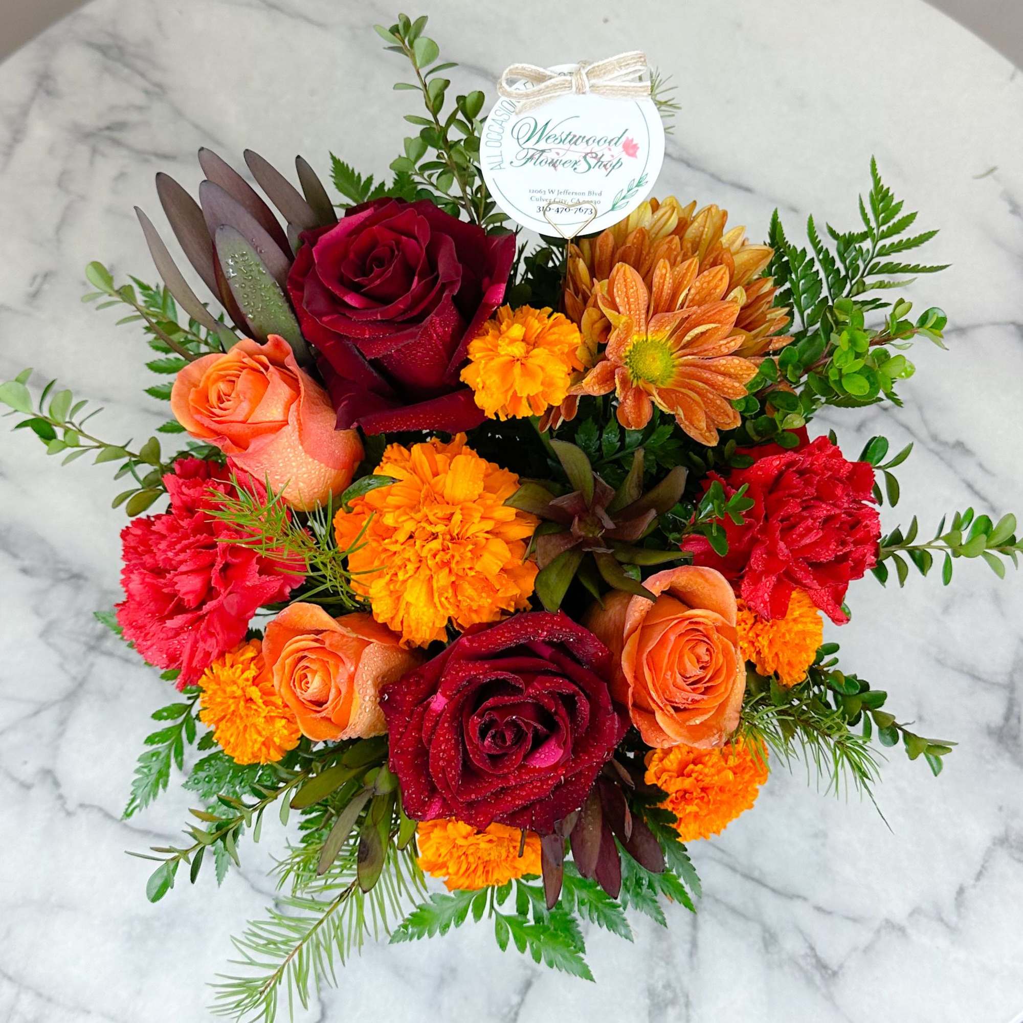 Bouquet of red and orange roses with marigolds and greenery