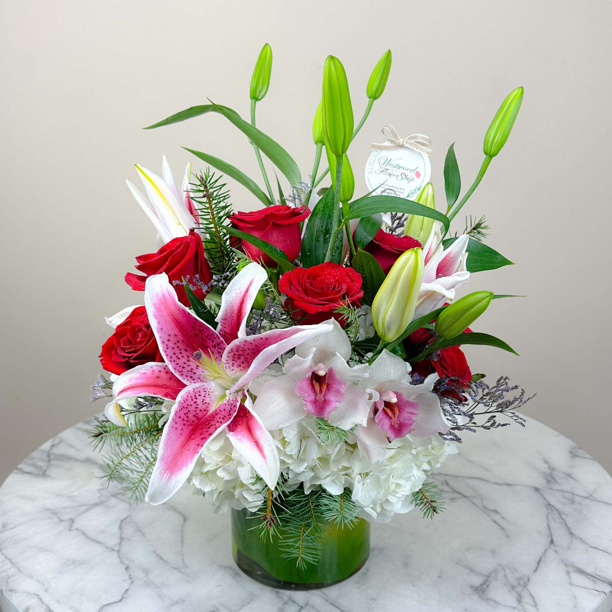 Bouquet of red roses and pink lilies in a green glass vase
