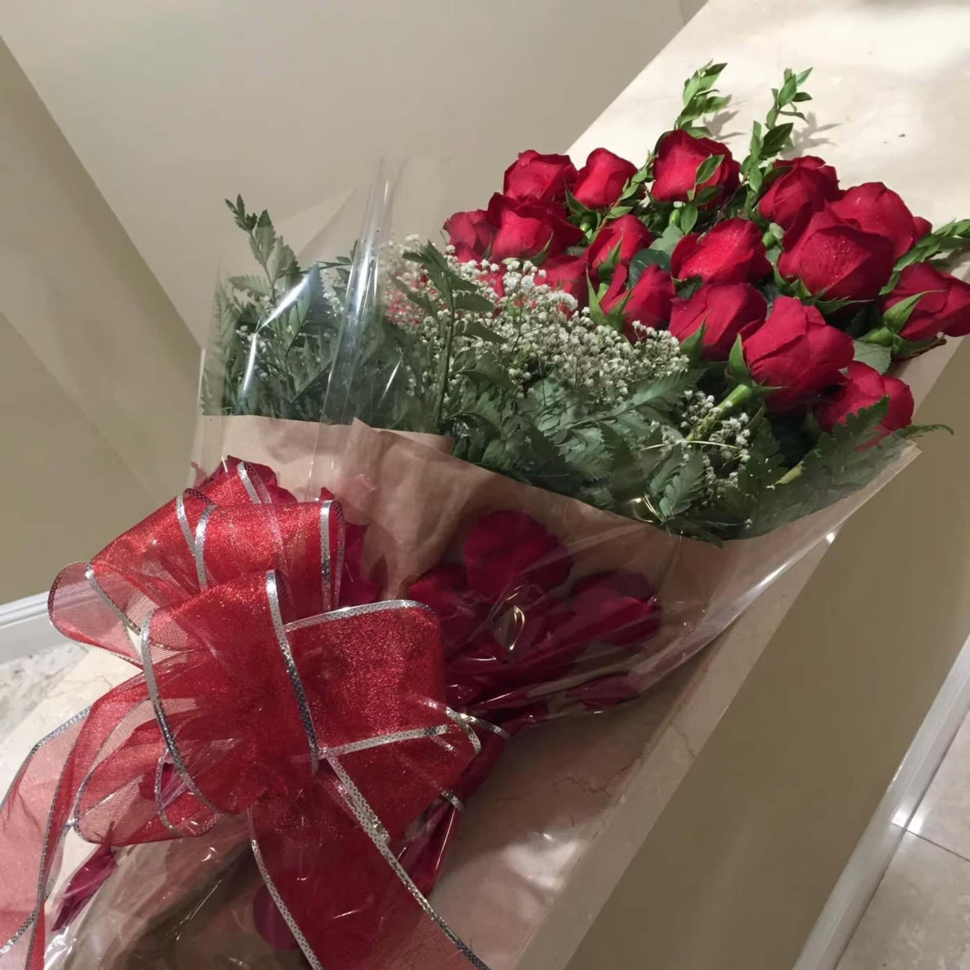 Bouquet of red roses wrapped in clear plastic with a large red bow