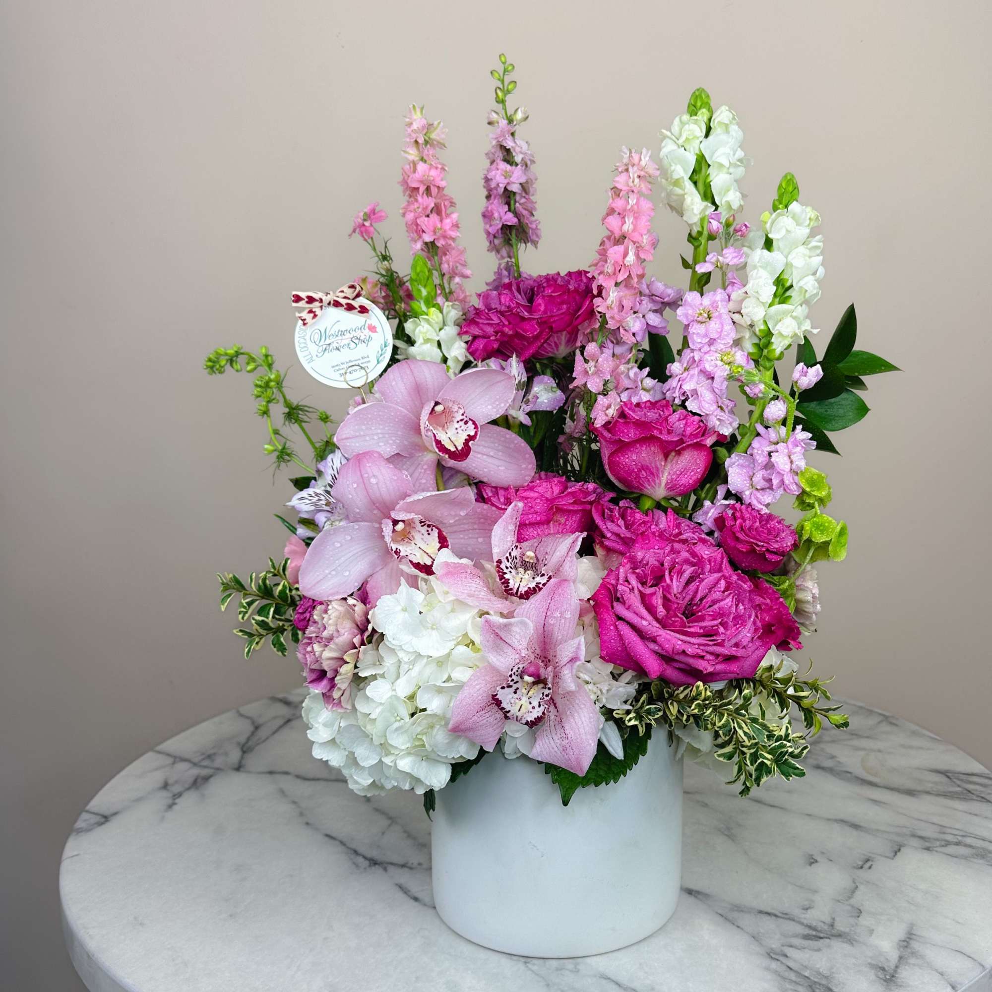 Pink orchids and roses arranged in a white vase