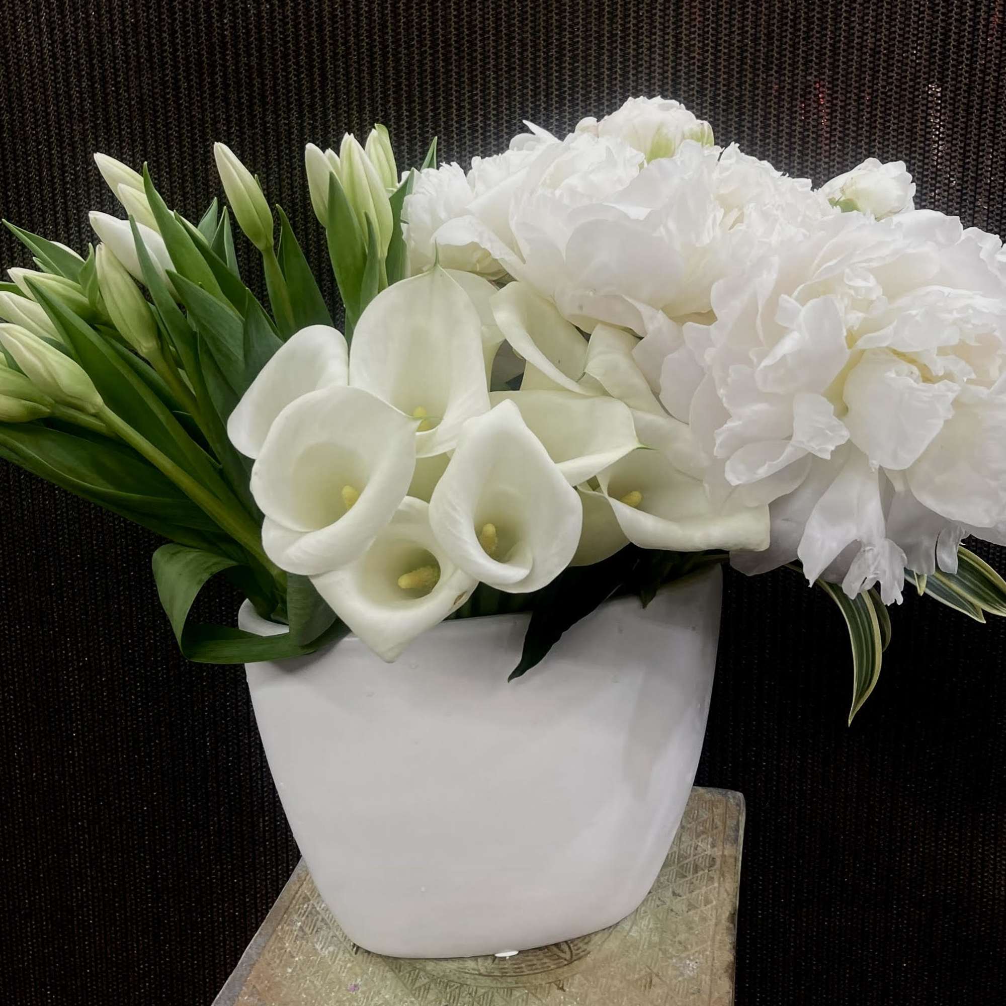 White calla lilies and peonies arranged in a white vase
