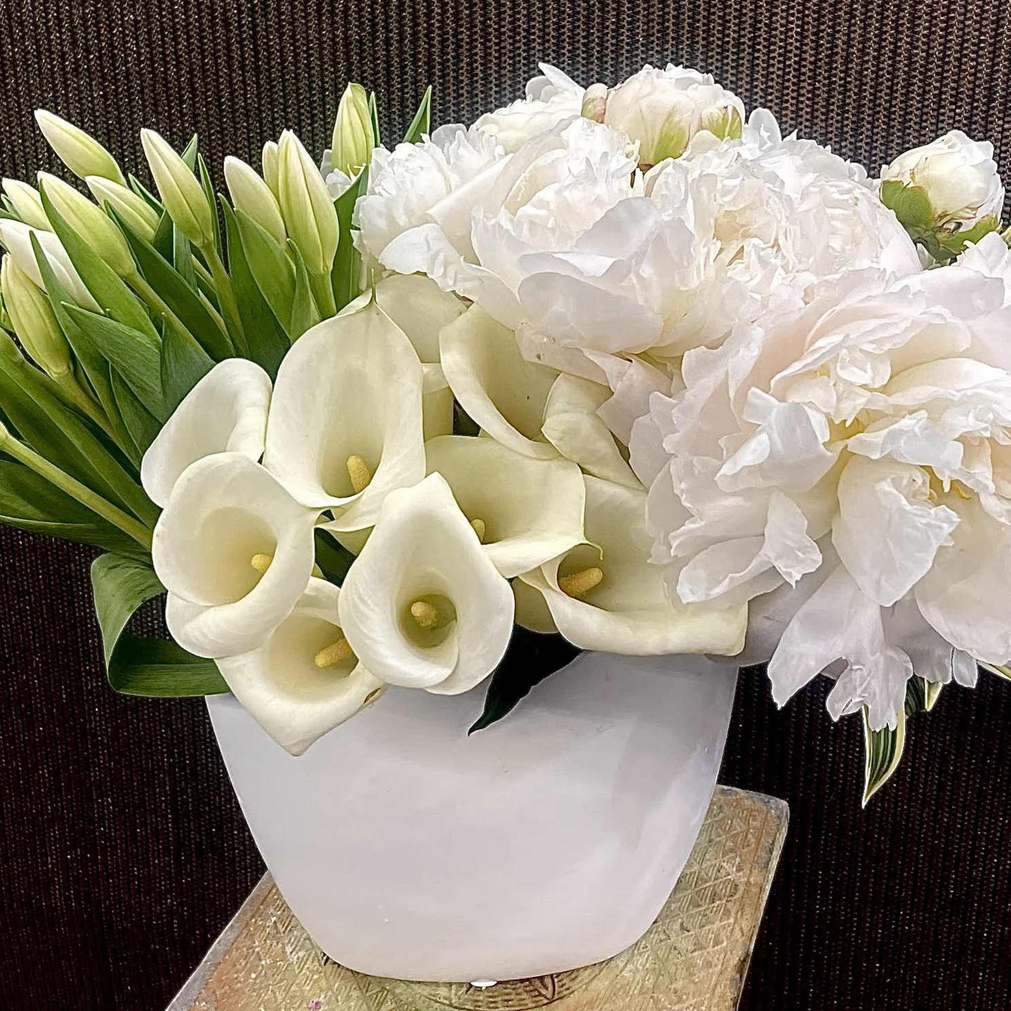 White calla lilies and peonies in a white vase