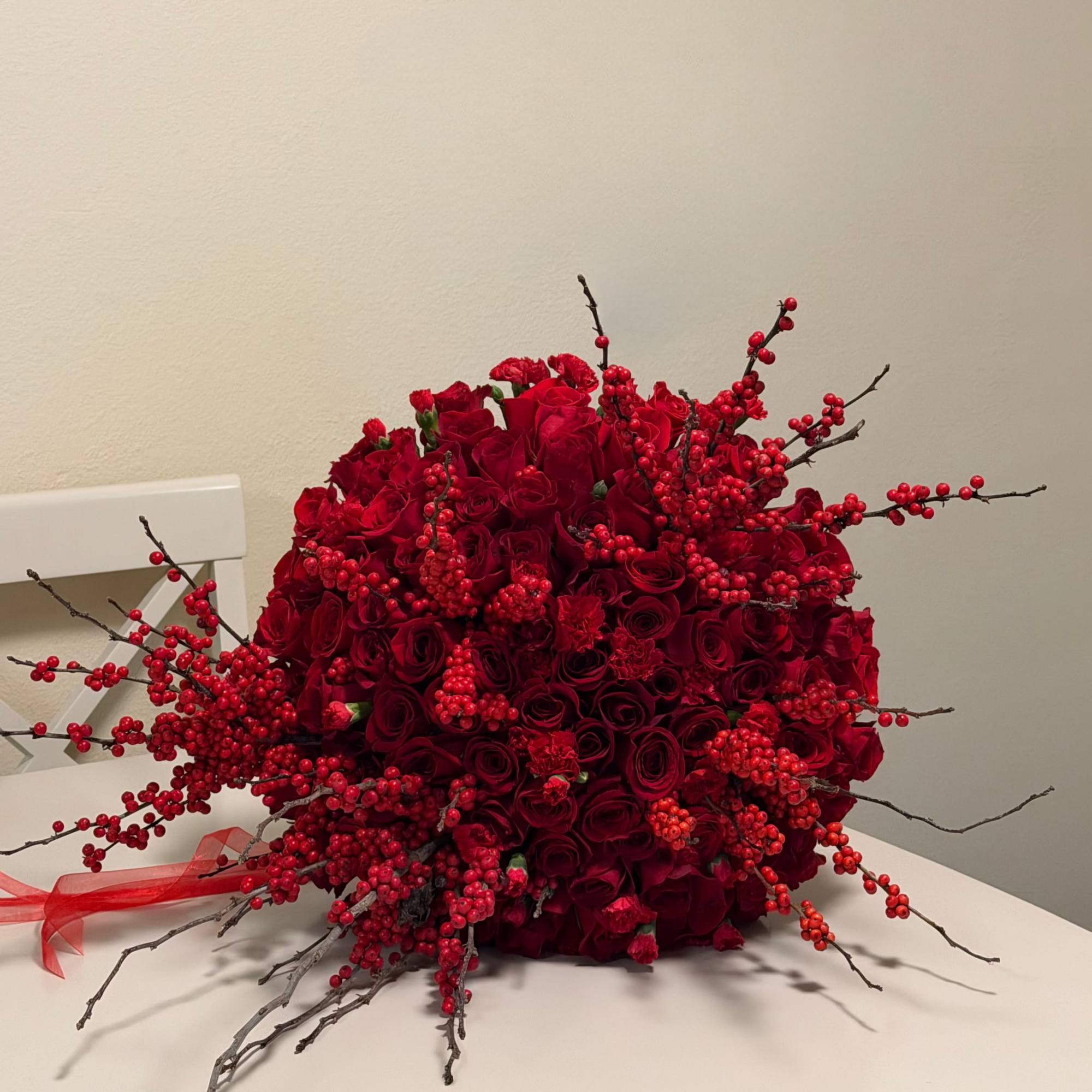 This striking arrangement features an abundant display of premium red roses, carnations