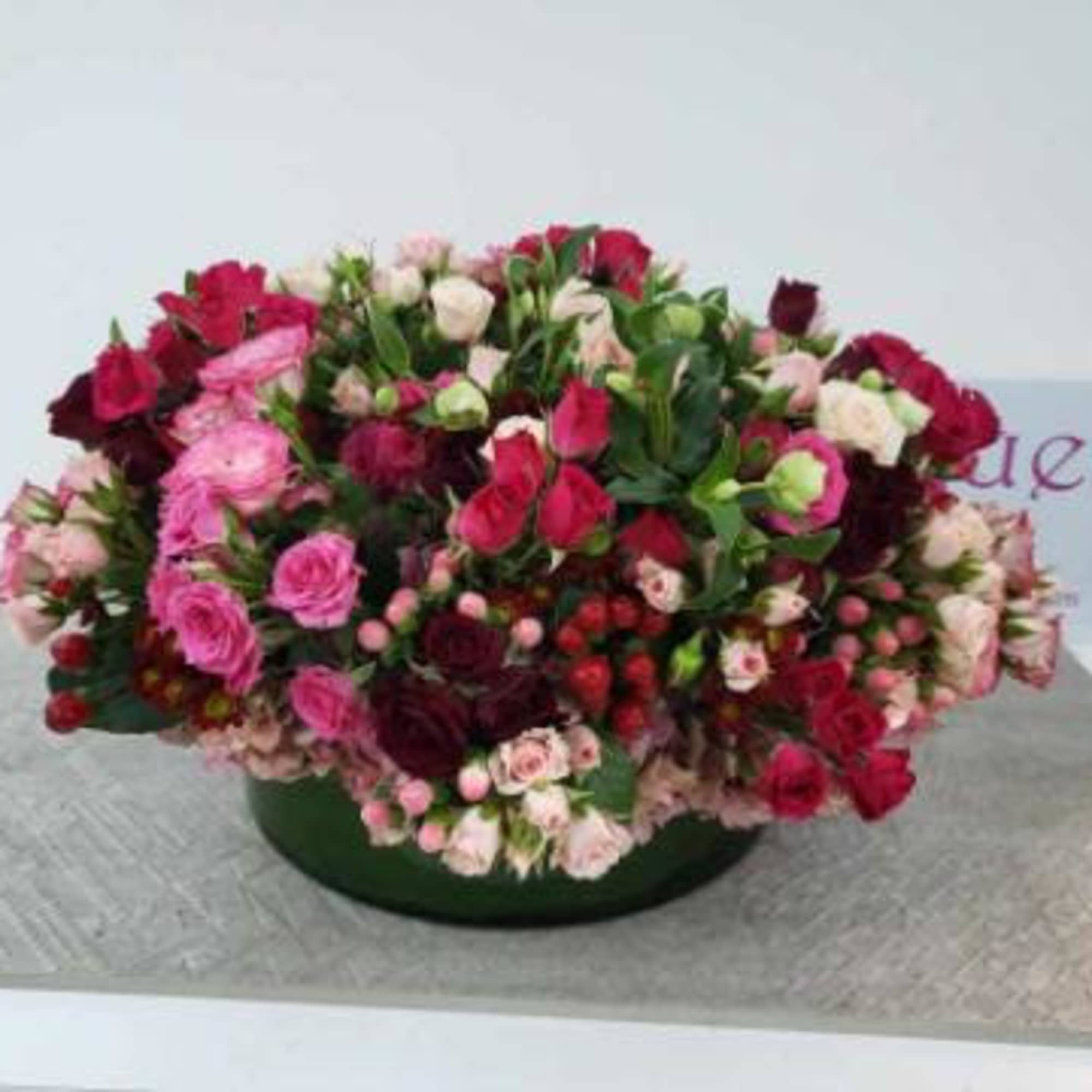 Large mixed bouquet of pink and red roses in a low green container