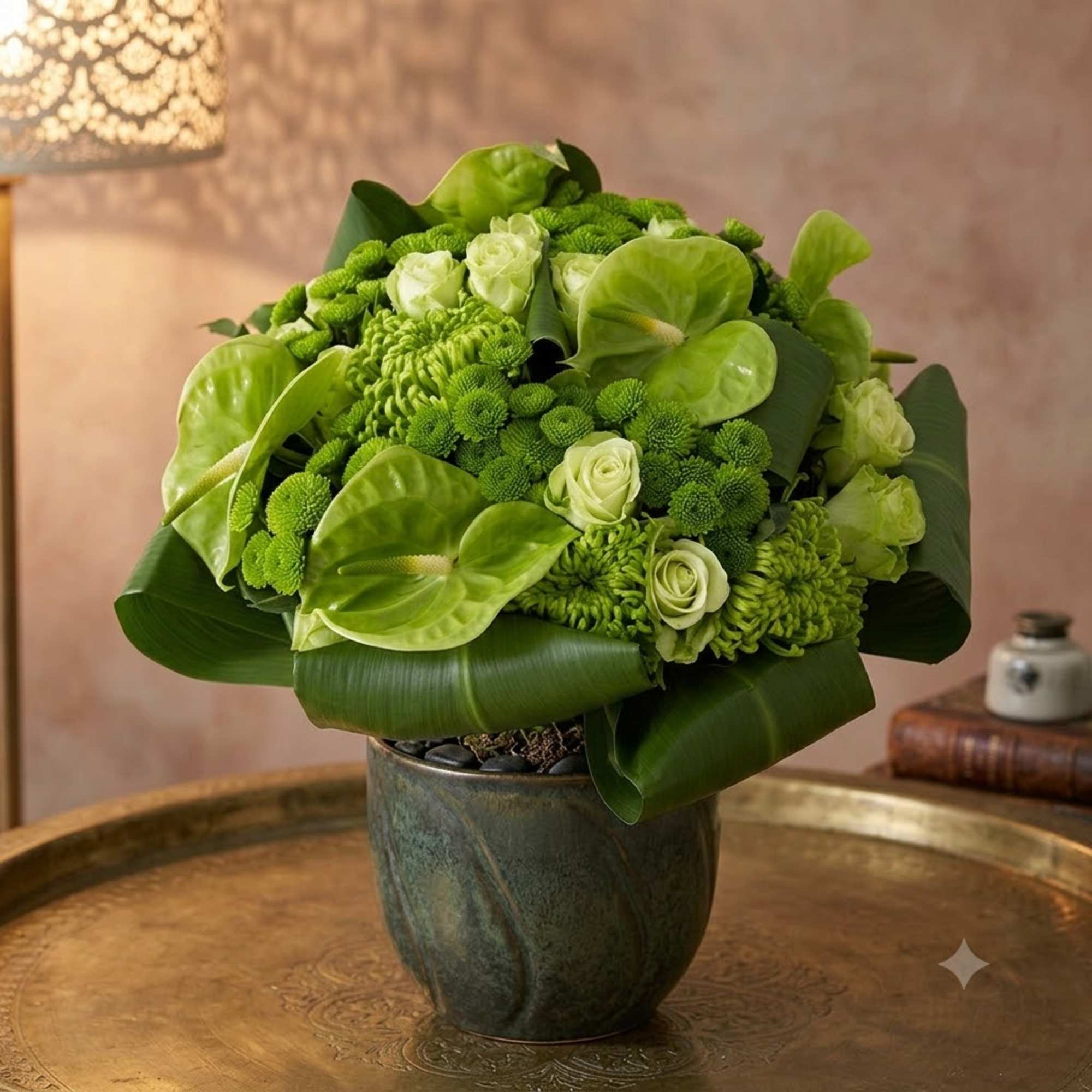 Green floral arrangement in a dark vase with broad leaves and pale blooms