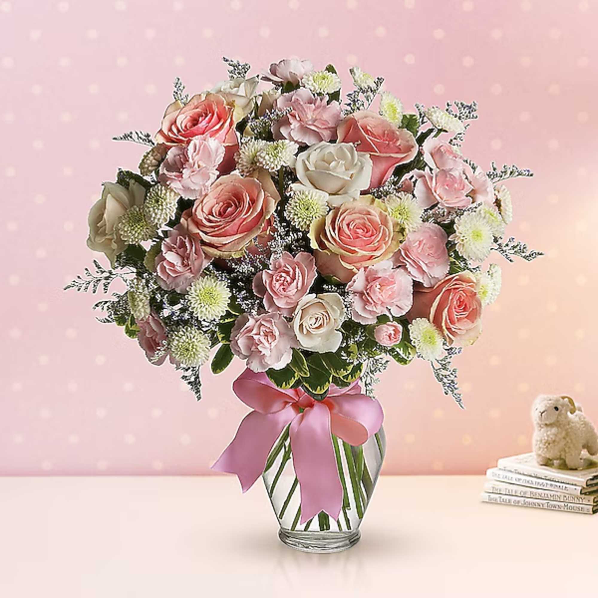 Pink and white rose bouquet in a glass vase with a pink ribbon