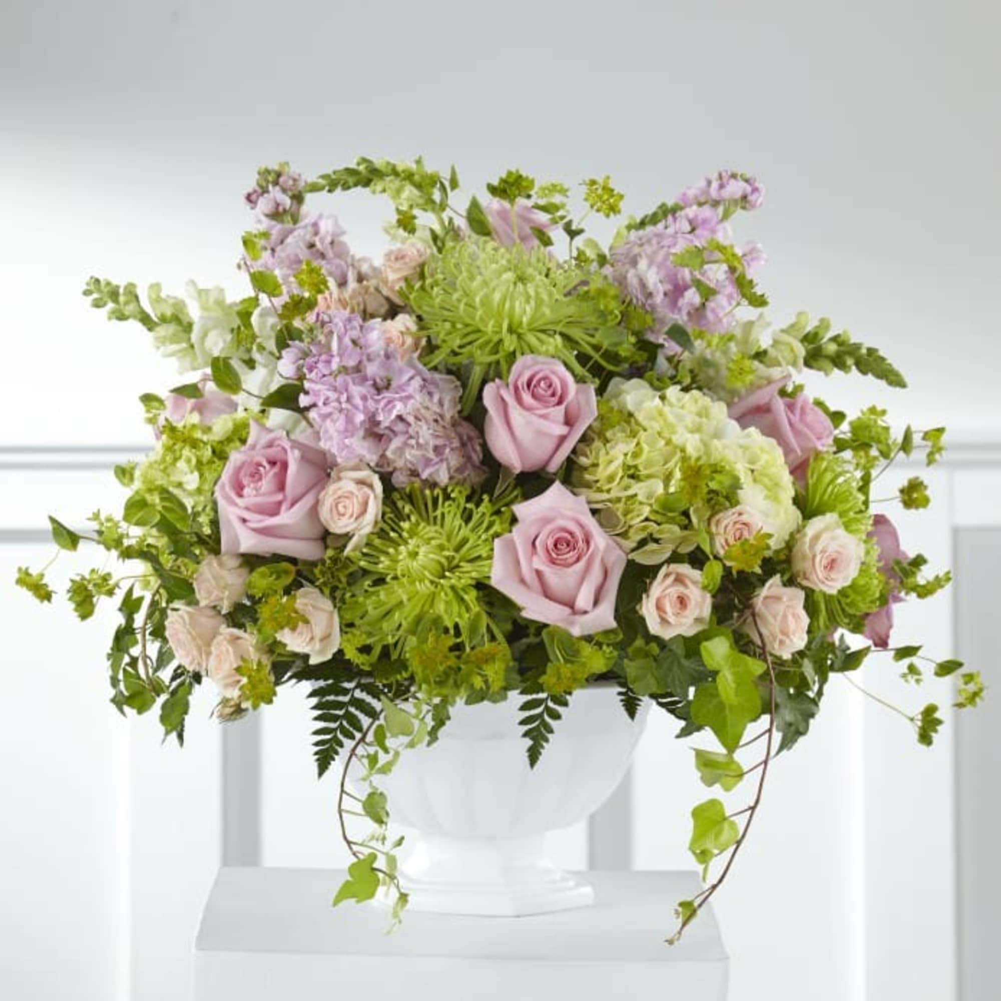 Pink roses and green blooms arranged in a white vase