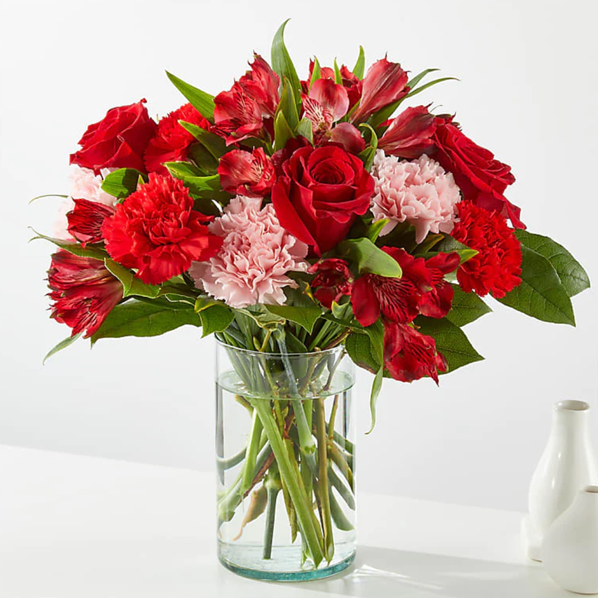 Red roses and carnations in a clear glass vase, photo 3 of 3