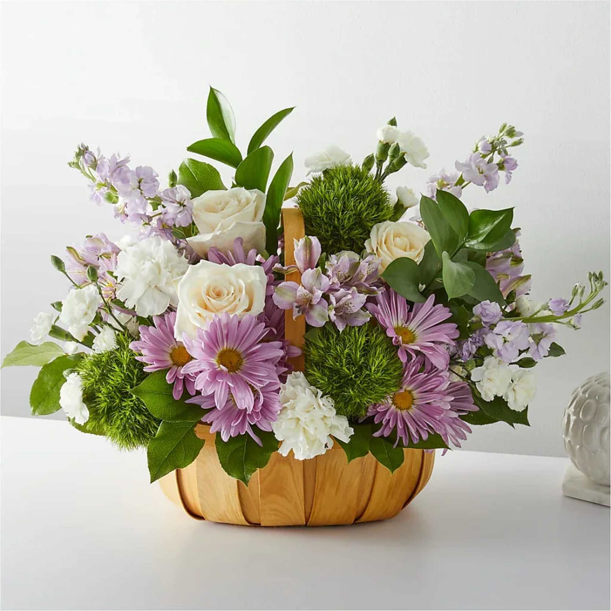Mixed bouquet in a pumpkin-shaped container with purple and white flowers