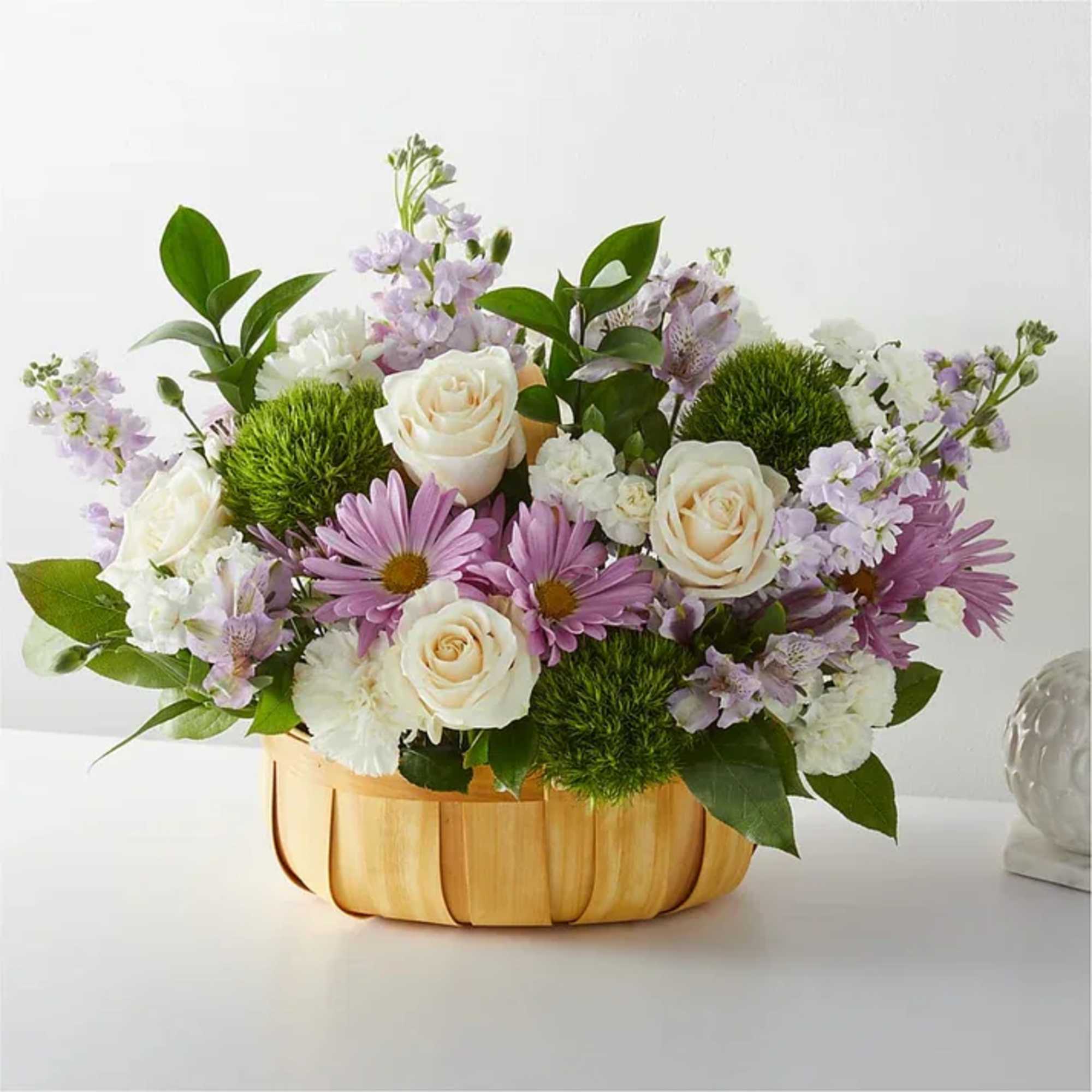 Lavender and white flower arrangement in a wooden basket