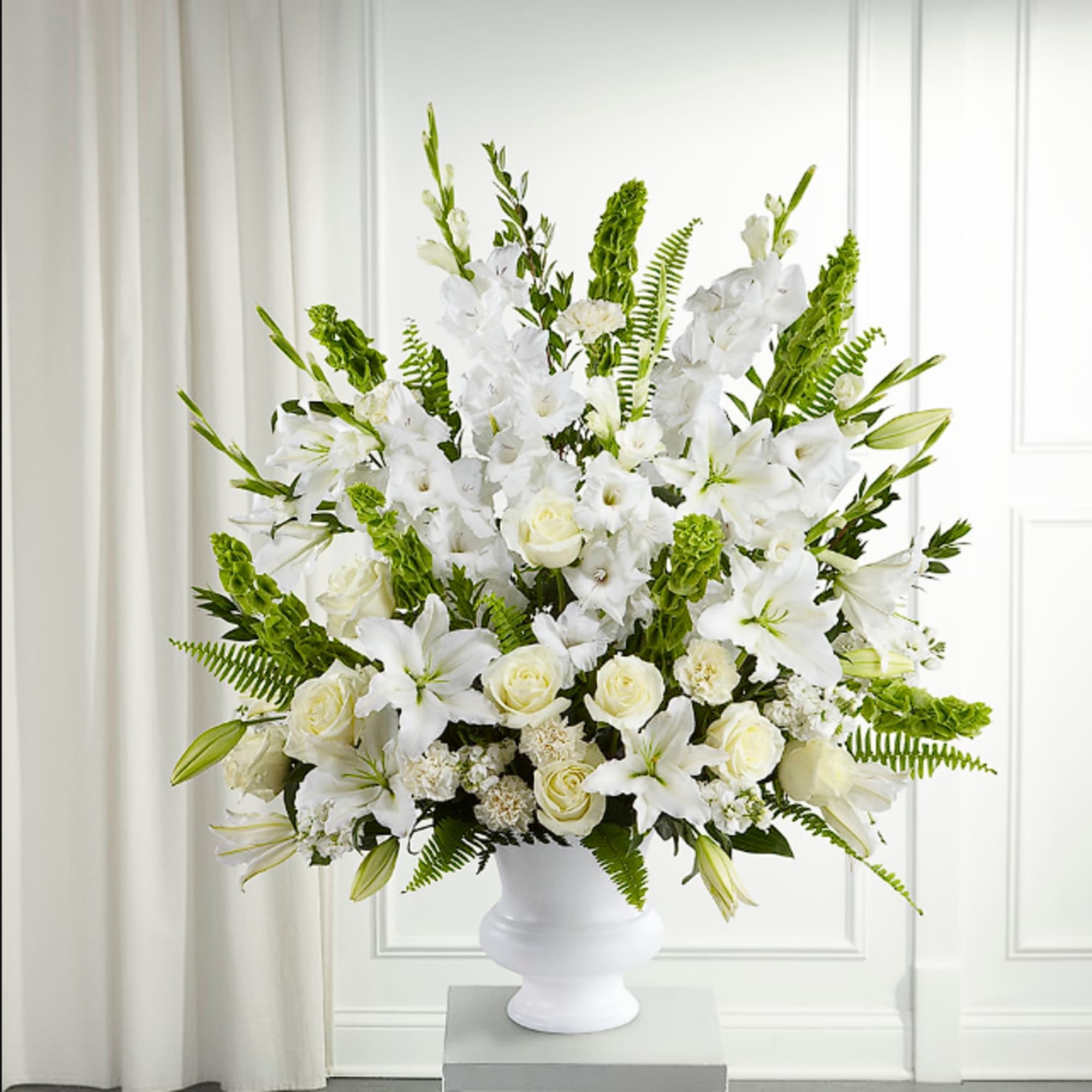White lilies and roses arranged in a white vase