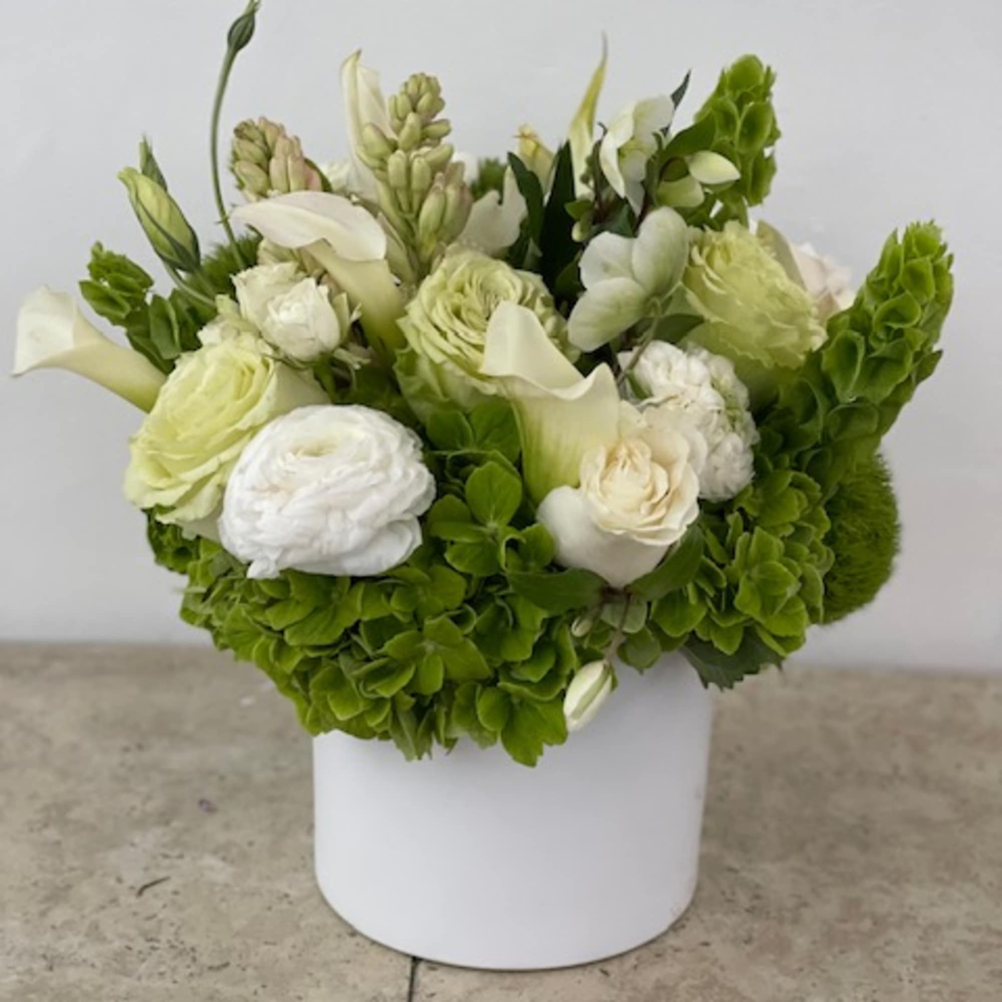White and green floral arrangement in a white box