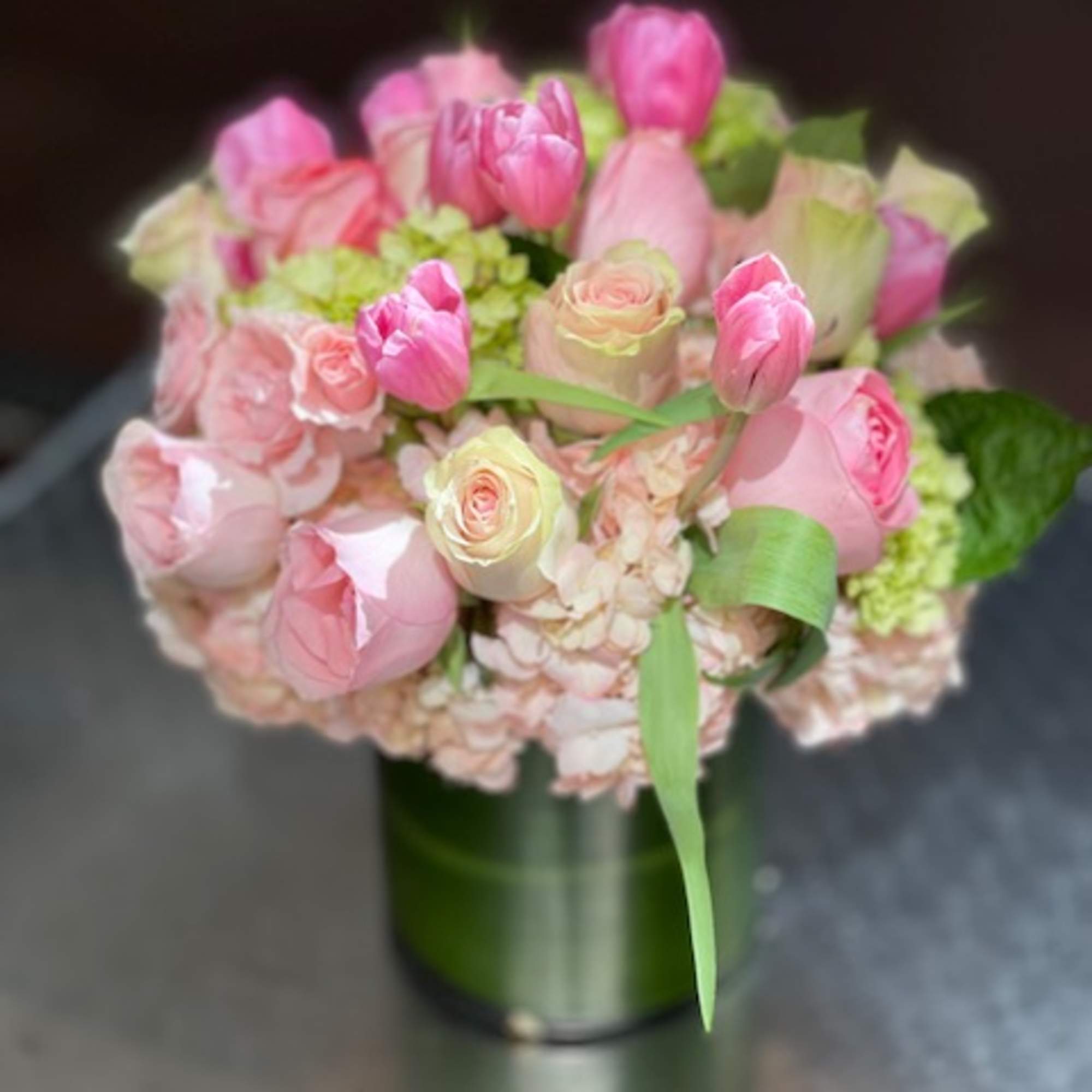 Pink tulips and roses arranged in a green vase