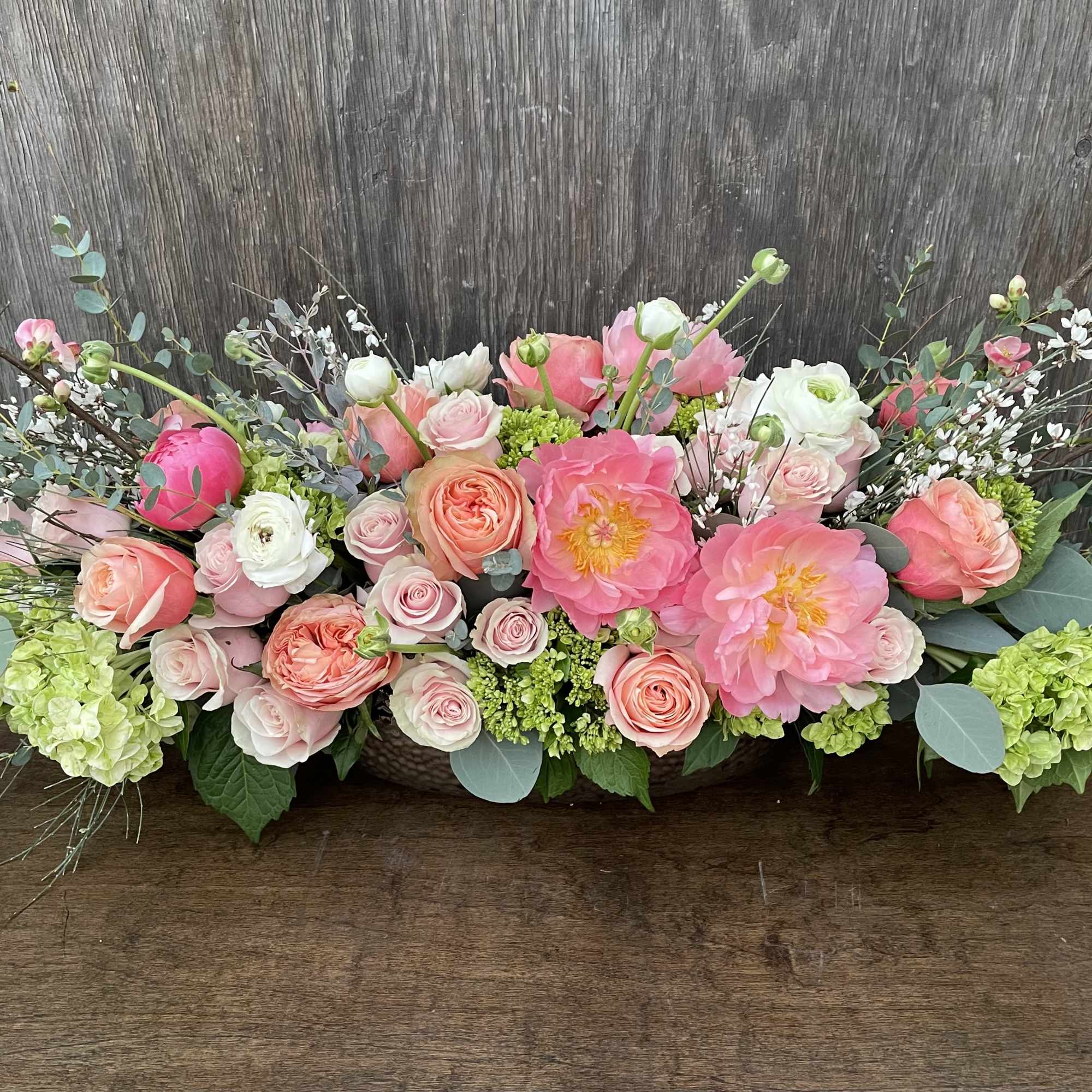 Low floral arrangement of pink and peach roses with large pink blooms