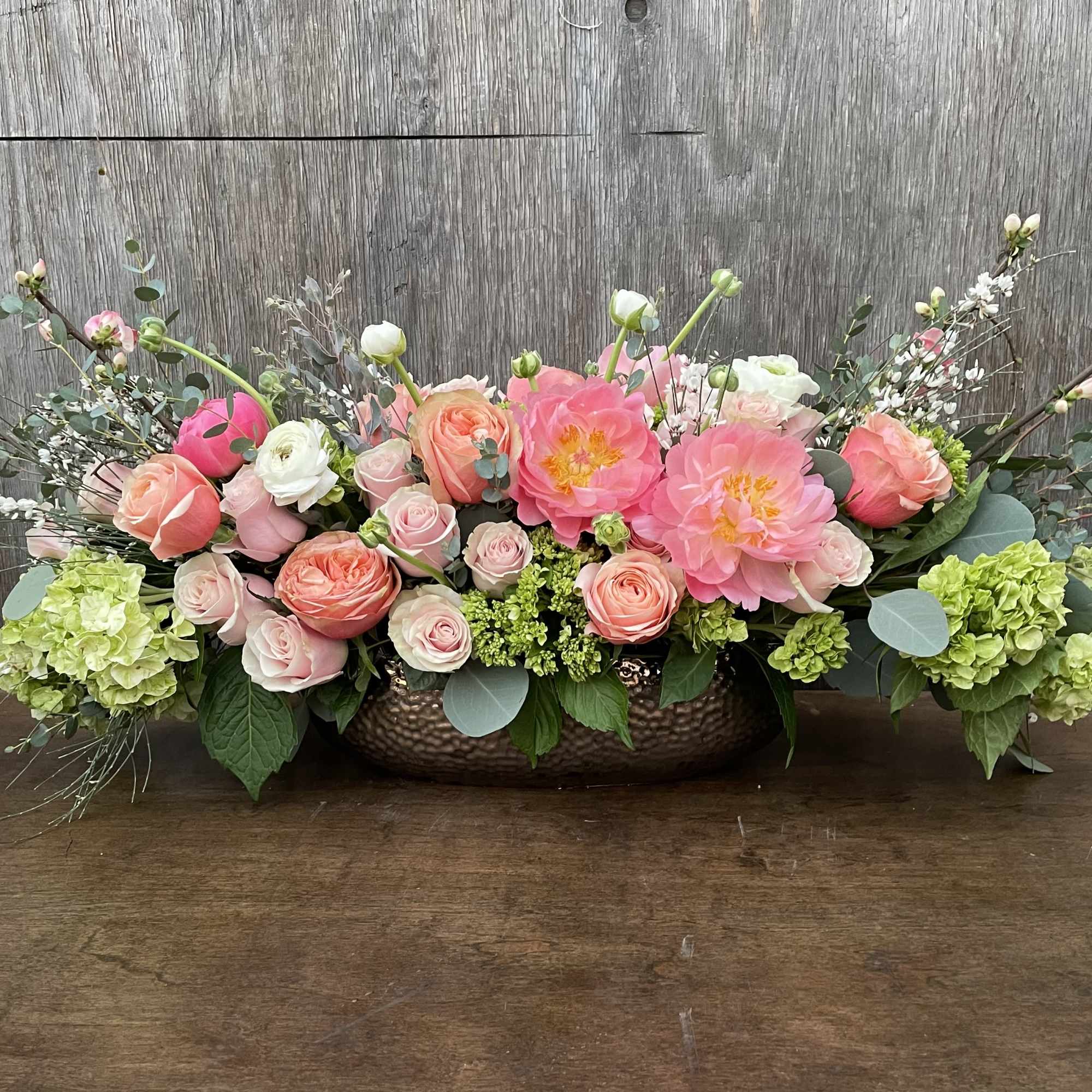 Low floral centerpiece with pink and peach blooms in a metal bowl