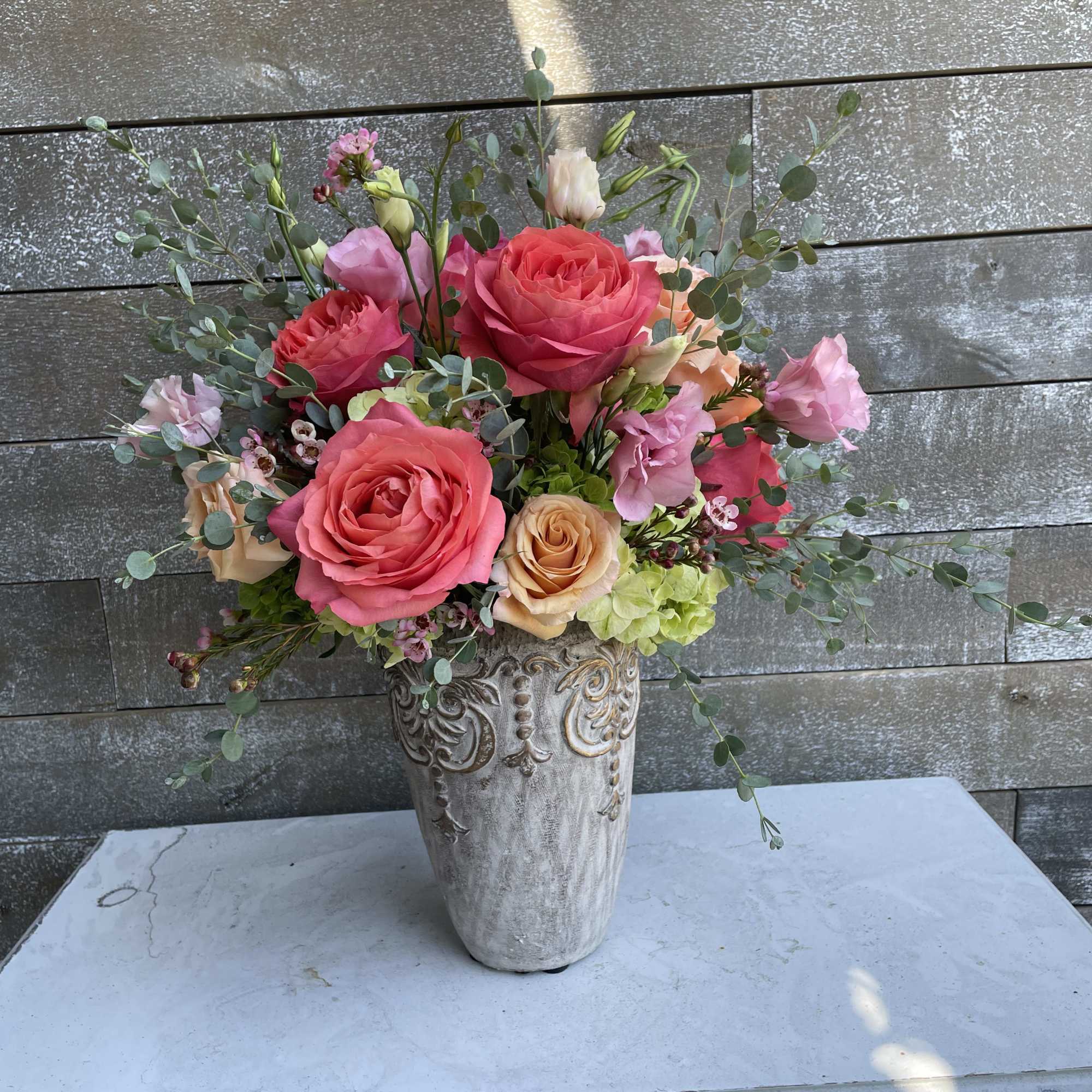 Pink and peach roses in an ornate vase
