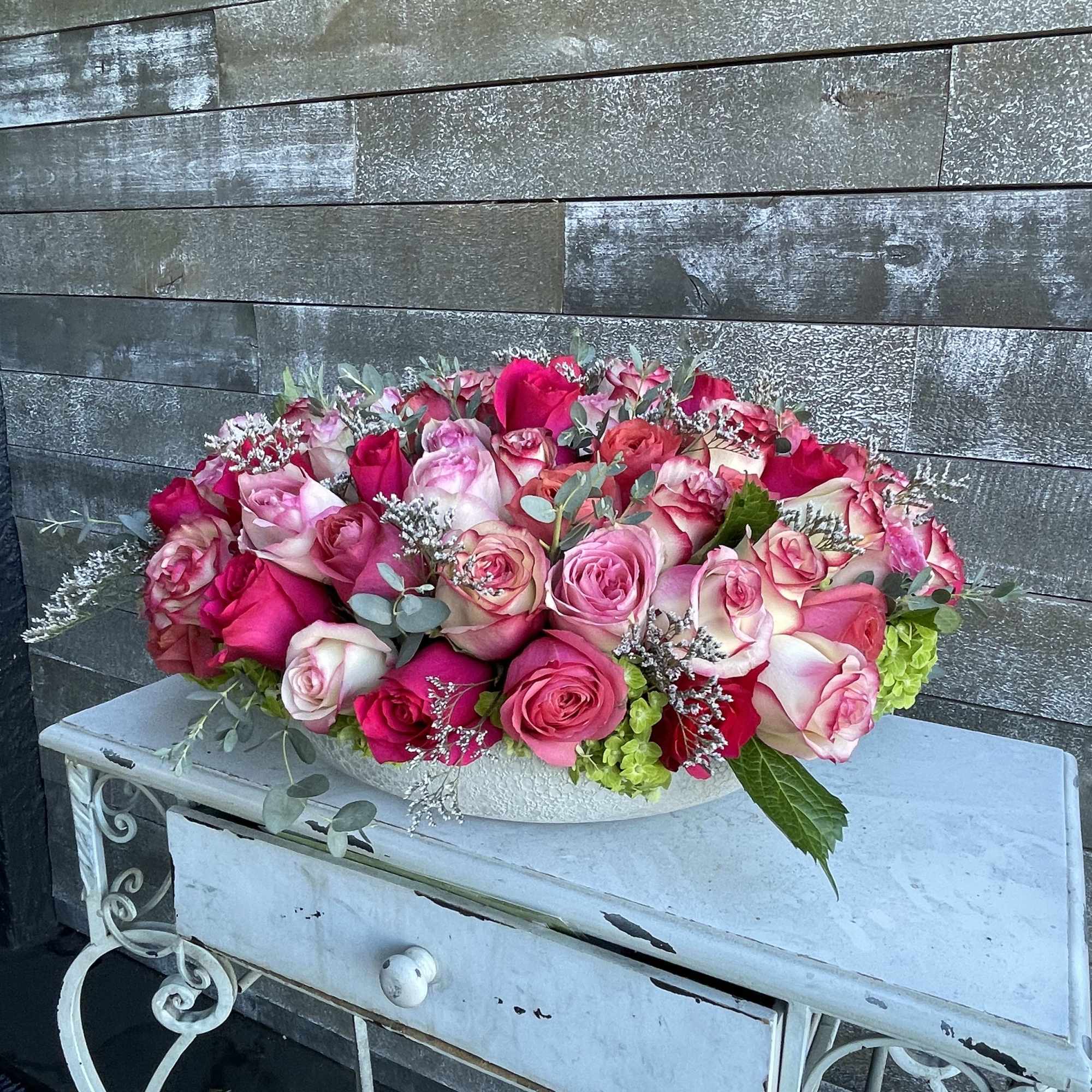 Pink and white rose arrangement in a low white container
