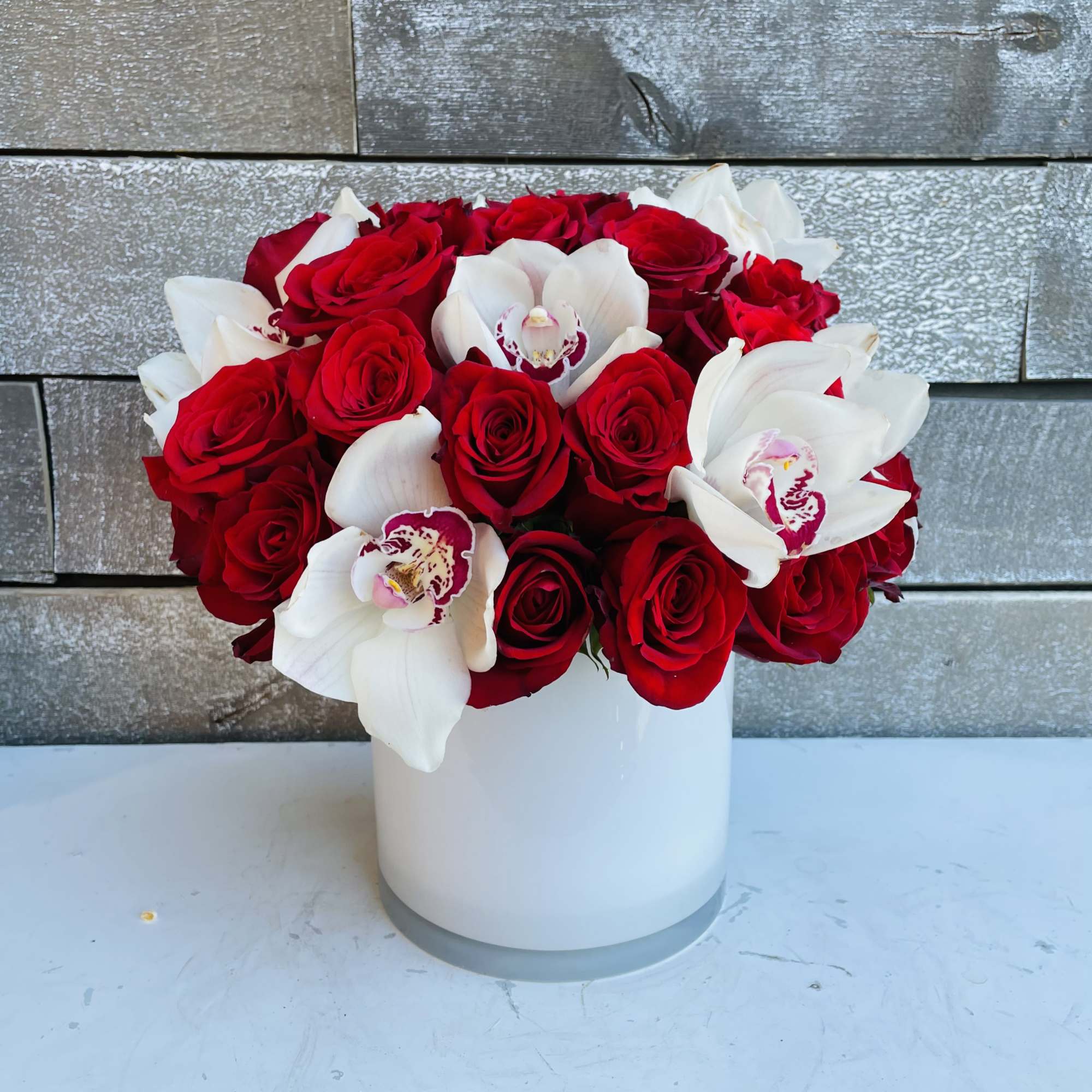 Red roses and white orchids arranged in a white vase, photo 2 of 3