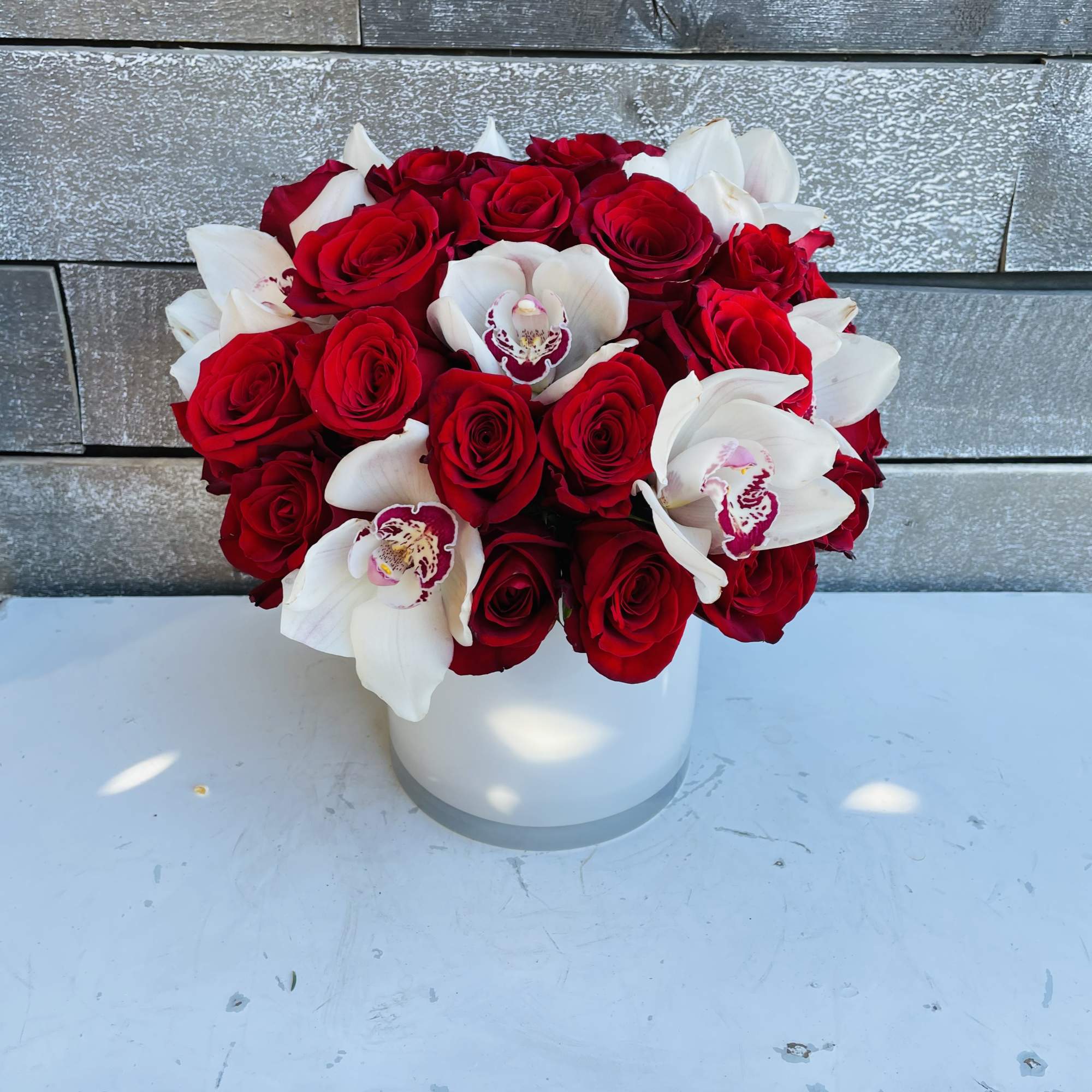 Red roses and white orchids arranged in a white vase, photo 3 of 3