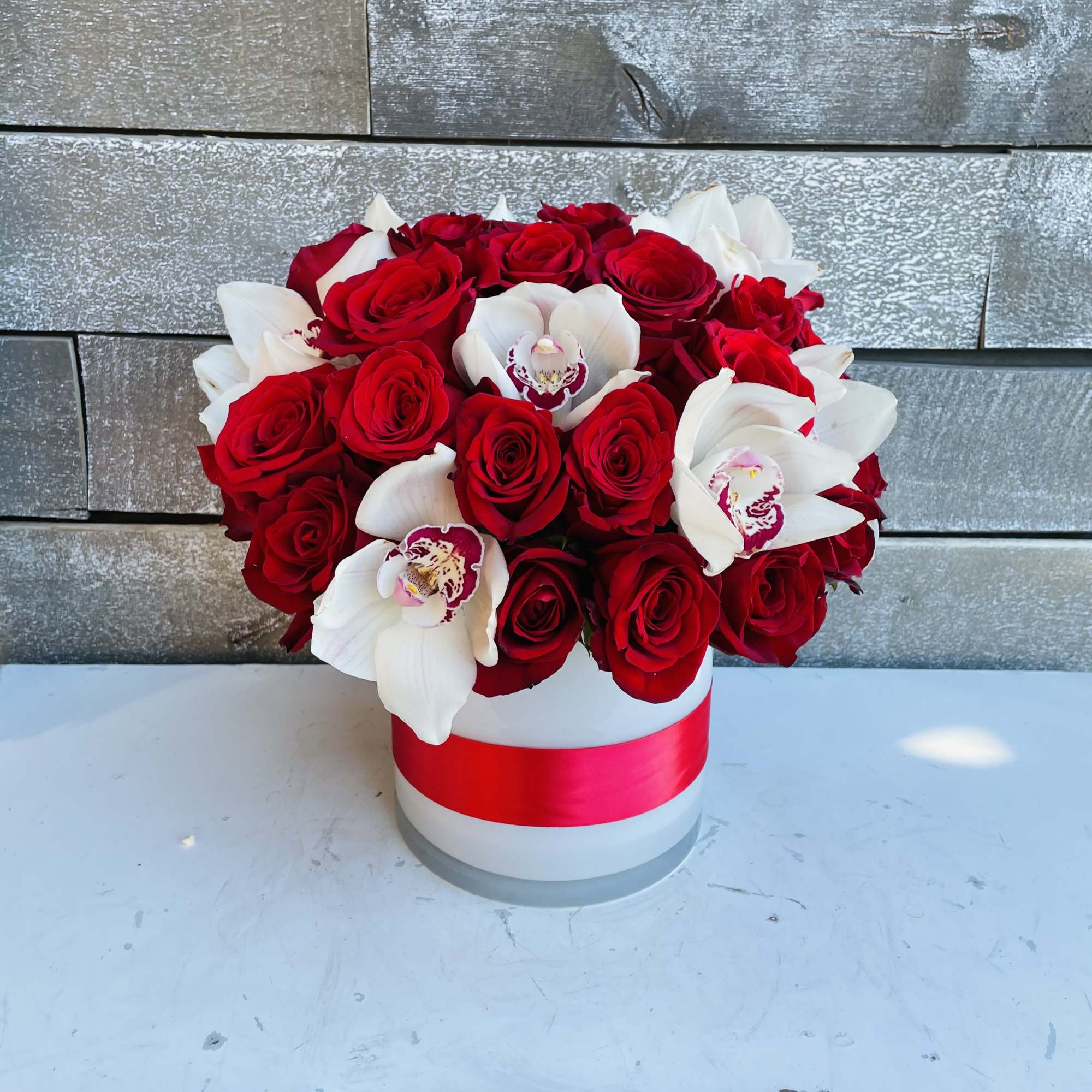 Red roses and white orchids in a white hat box with a red ribbon, photo 3 of 4
