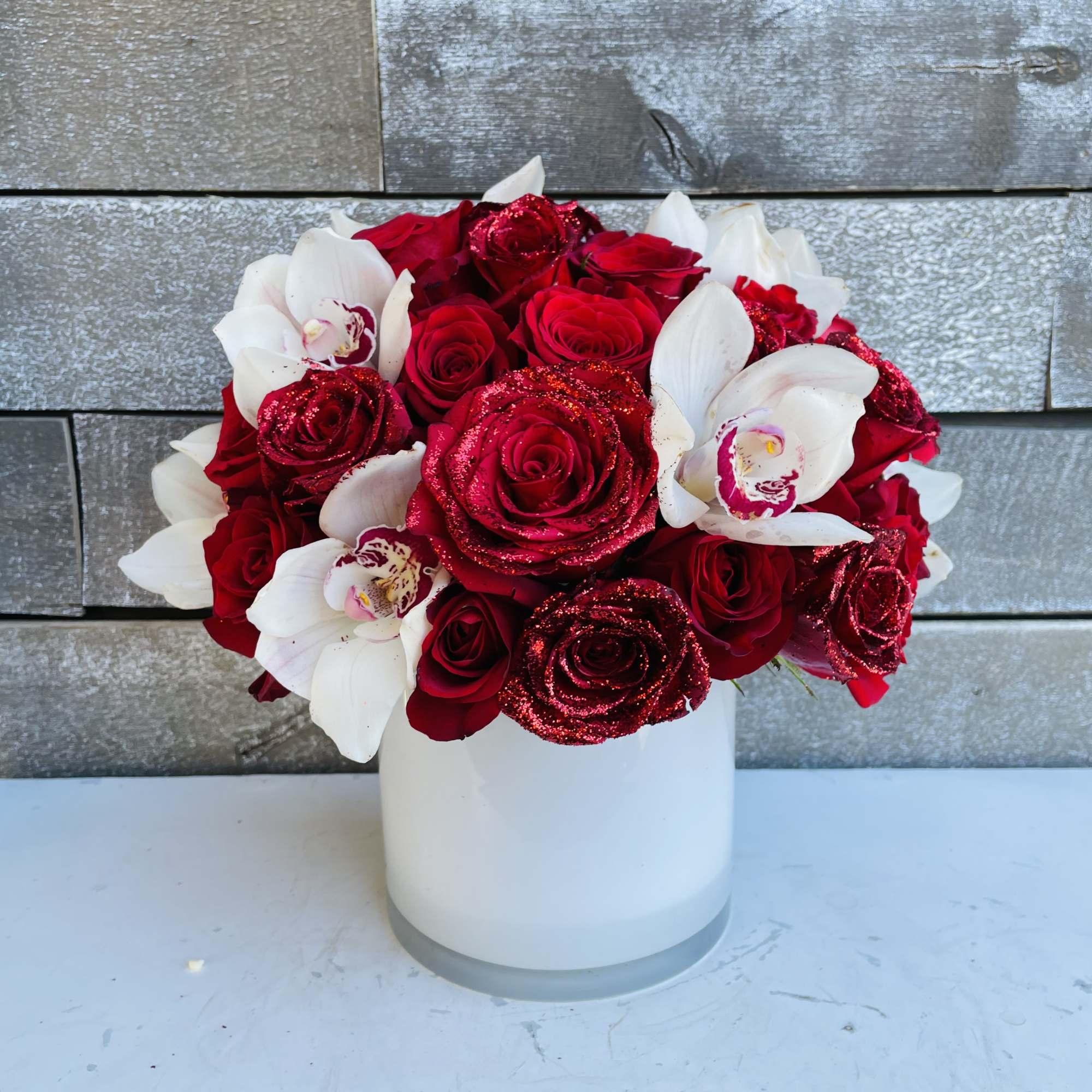 Red roses and white orchids arranged in a white vase