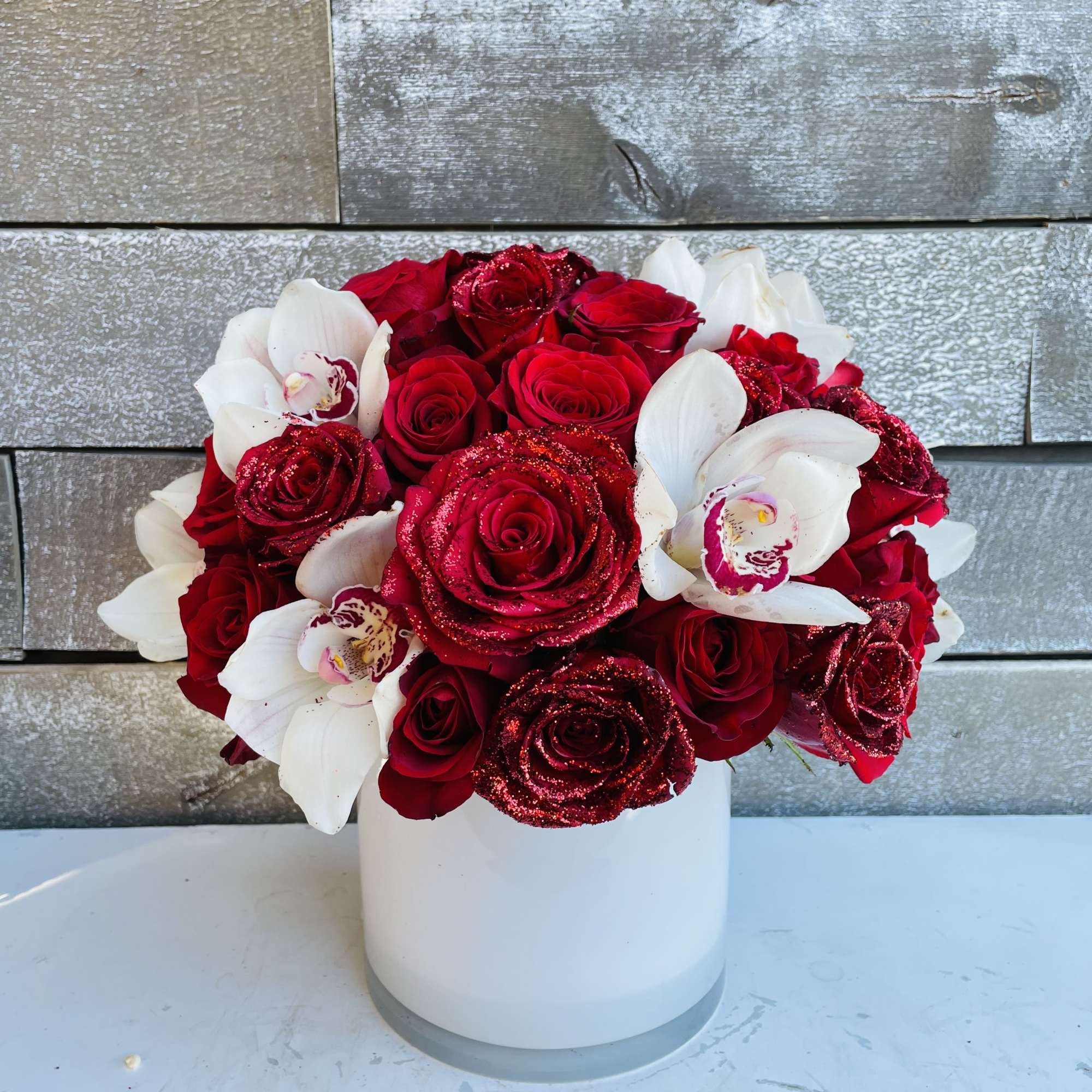 Red roses and white orchids arranged in a white vase, photo 3 of 4