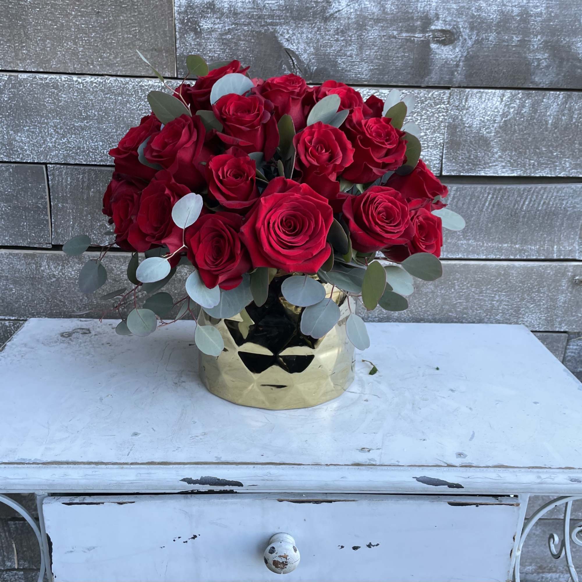 Red roses arranged in a gold vase with eucalyptus accents, photo 2 of 4