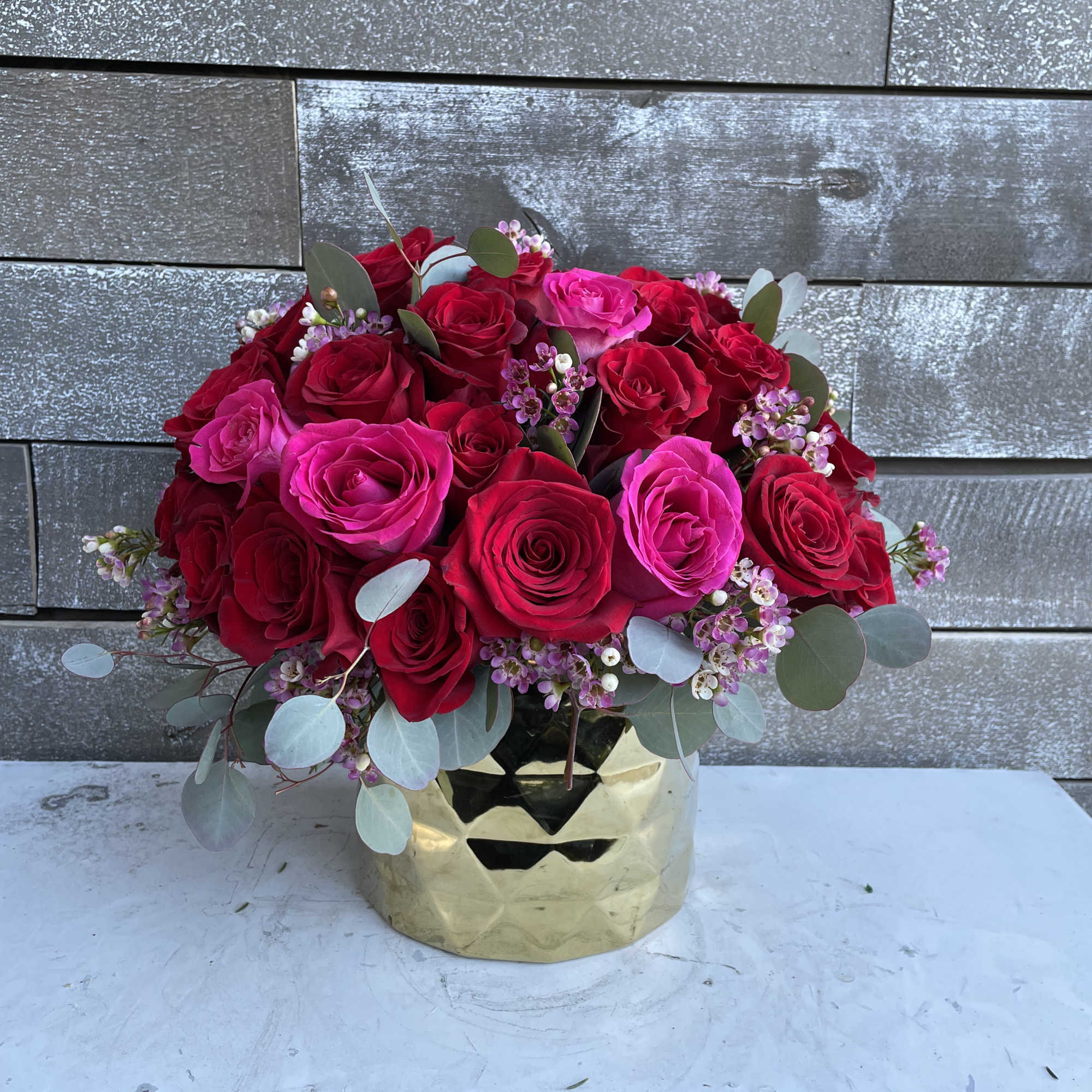 Bouquet of red and pink roses in a gold vase