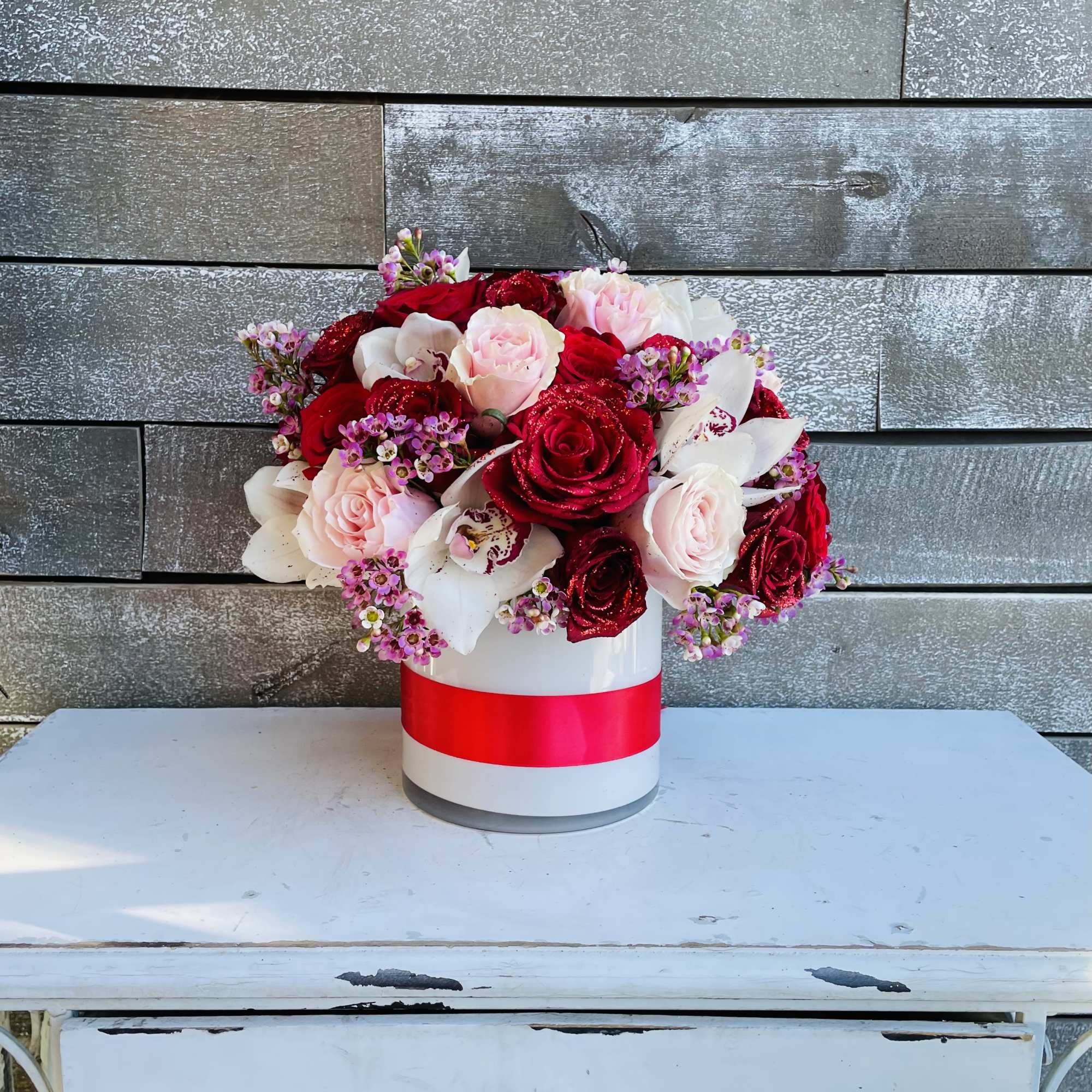 Bouquet of red and pink roses in a white hatbox with a red ribbon