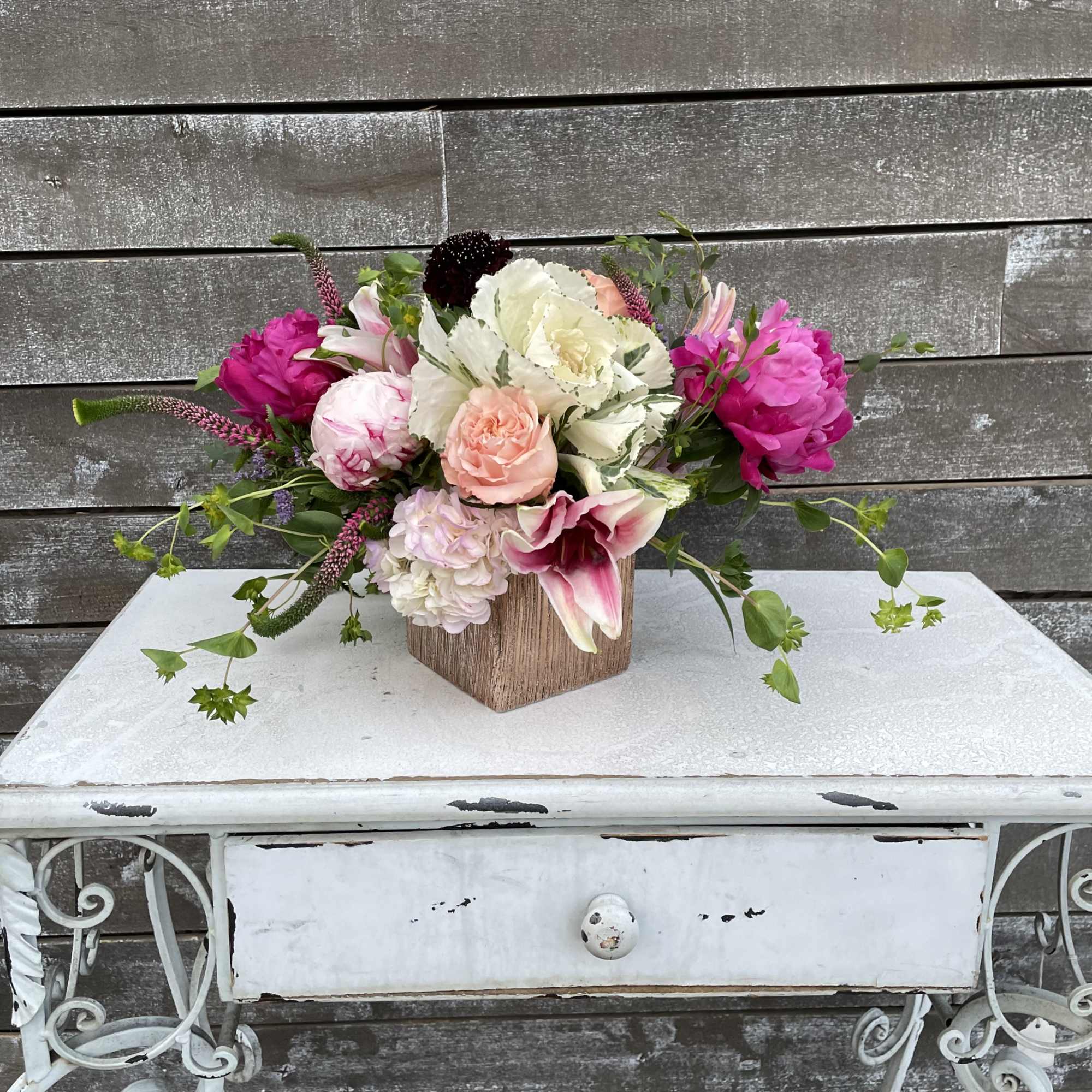 Pink and white floral arrangement in a wooden cube vase