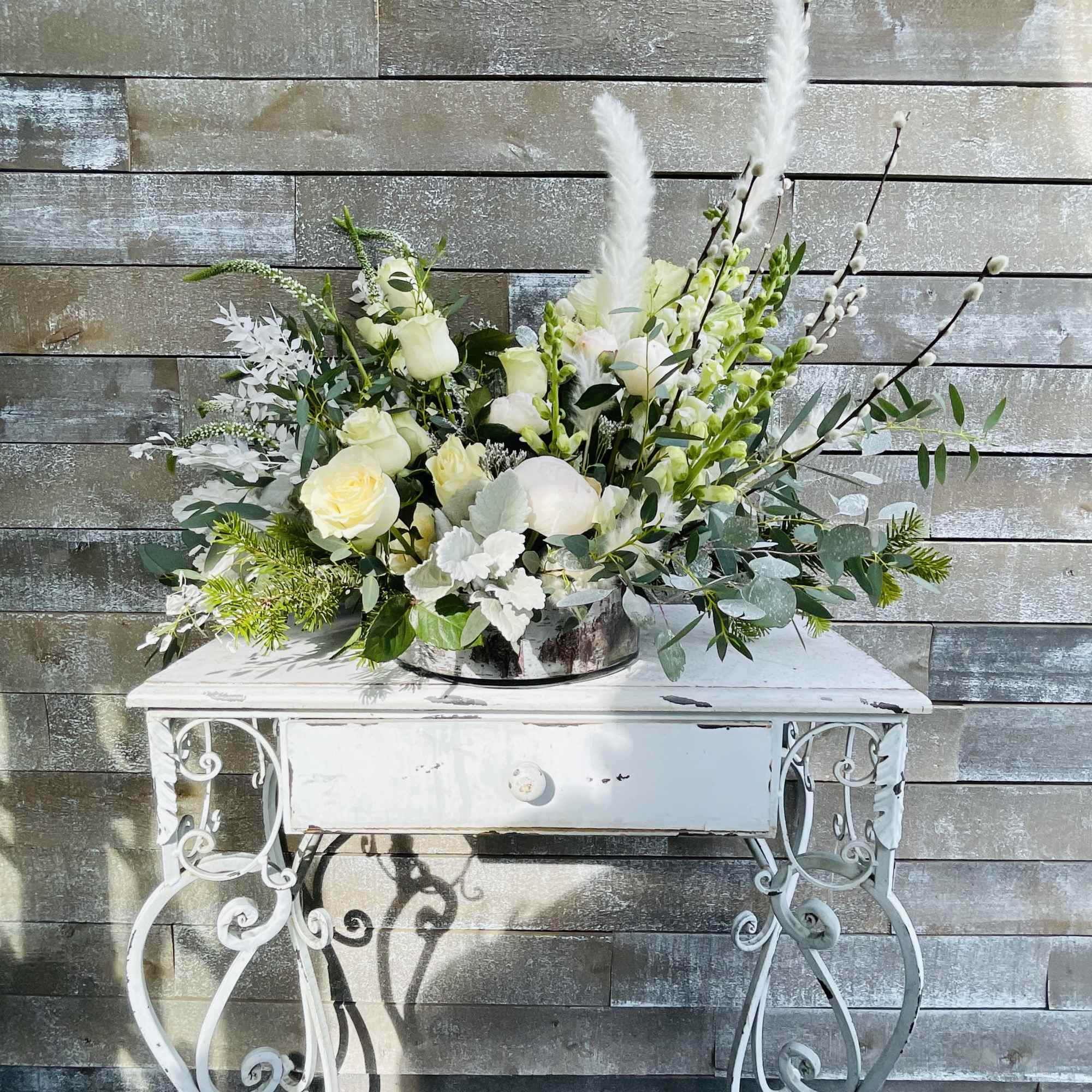 White floral arrangement in a silver bowl on a white table